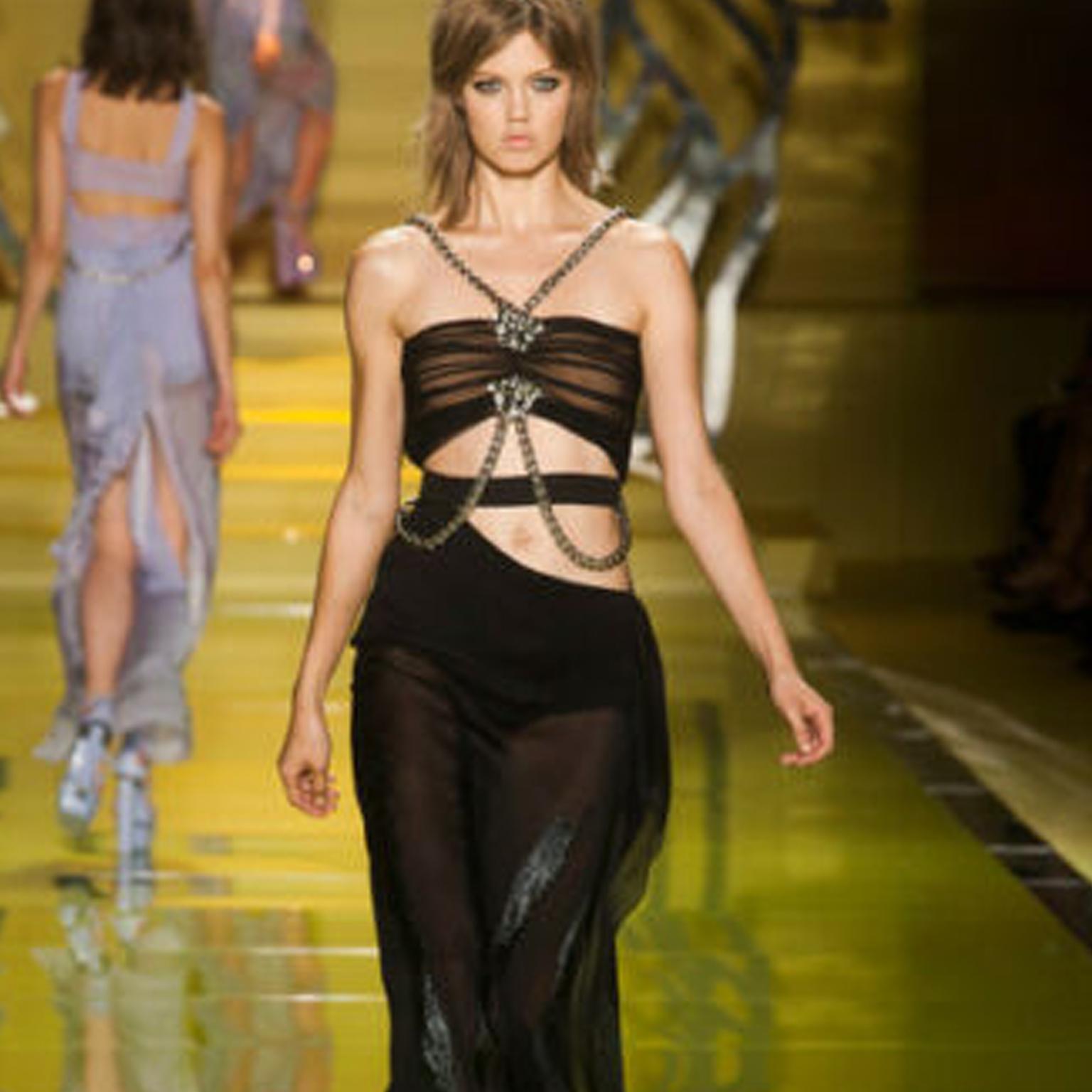 VERSACE
FROM THE SPRING SUMMER 2014 RUNWAY FINAL LOOK
Silk, polyester, polyamide, elastane. Black ruched bustier with nude lining. Silver-tone Medusa pin at bustier top. Attached chunky metal chain harness. Cut out at waist. Attached elastane boy