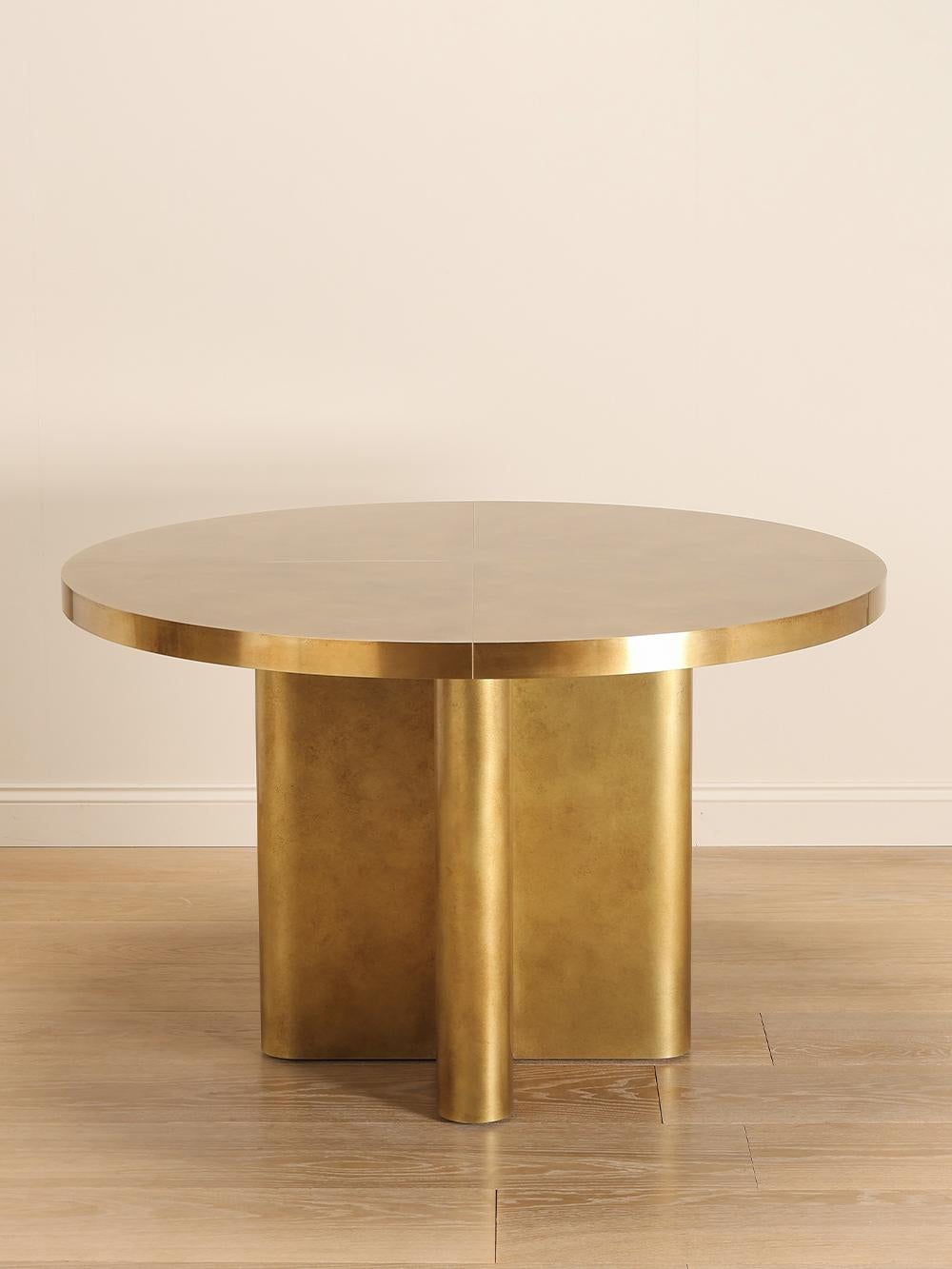 Table de salle à manger circulaire en laiton légèrement marbré avec une base géométrique. Cette pièce reflète la patine et l'enrobage de laiton caractéristique de Rupert Bevan sur toute la surface.