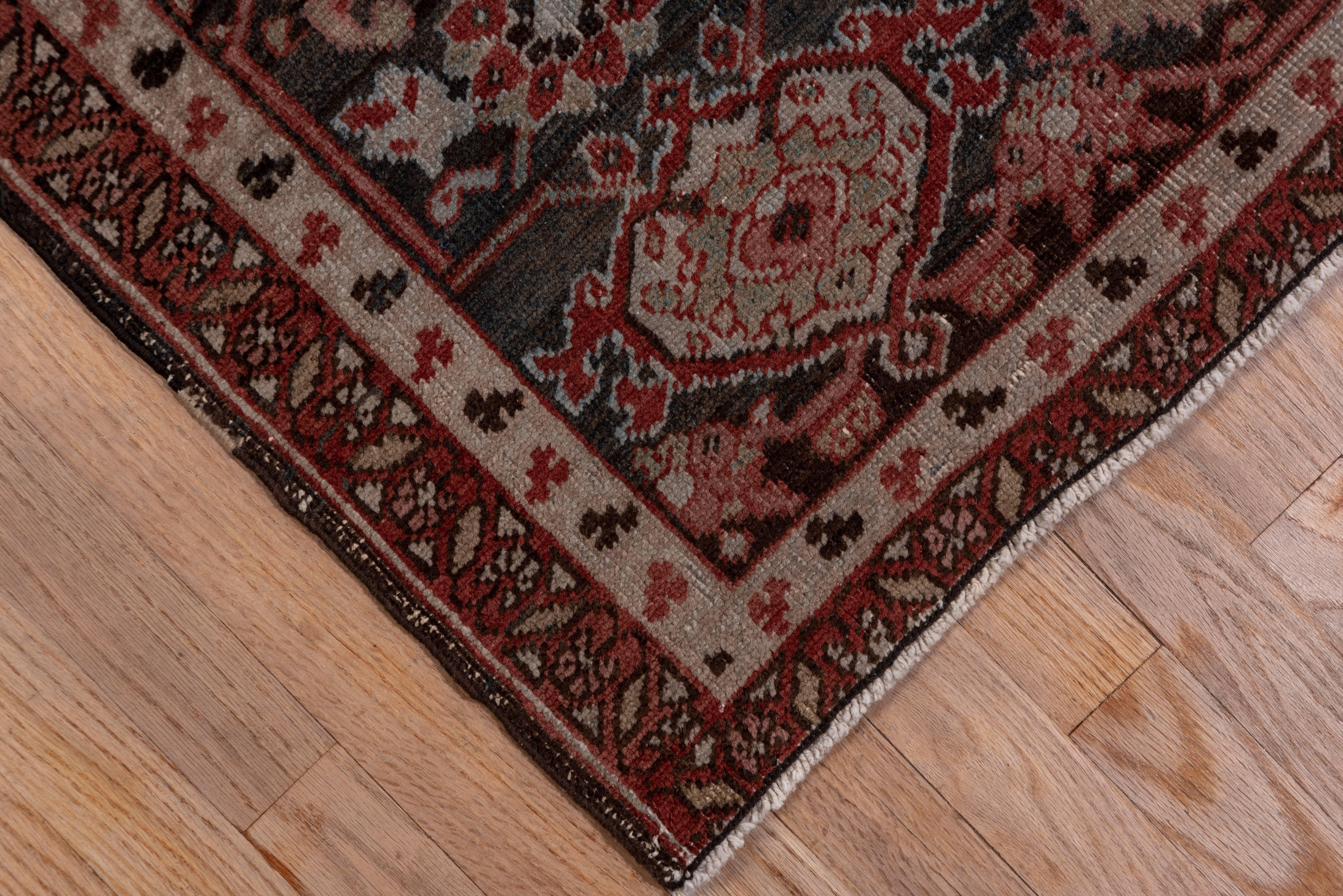 Of tighter 'Serapi' quality, this NW Persian rural carpet is heavily work, but it still retains genuine character with its red subfield centring a huge navy octogramme pendanted medallion. The extended ivory corners have serrated leaf motives. The