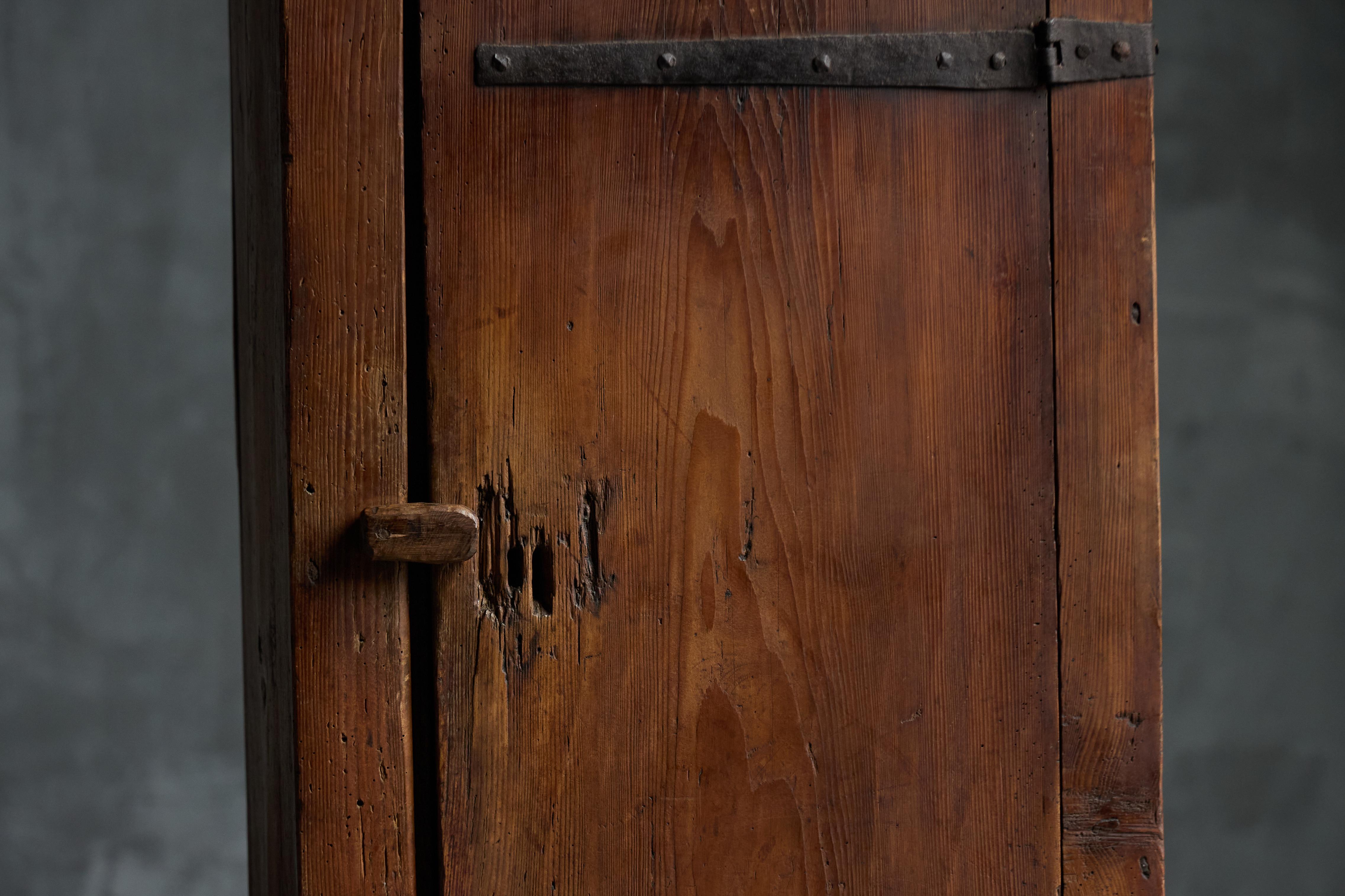 Beautifully handcrafted bonnetière that embodies the enduring craftsmanship of 19th-century rural France. Made from solid pine, this paysan-style cabinet hails from the Auvergne region. Its unadorned design, with visible hand-wrought iron hardware