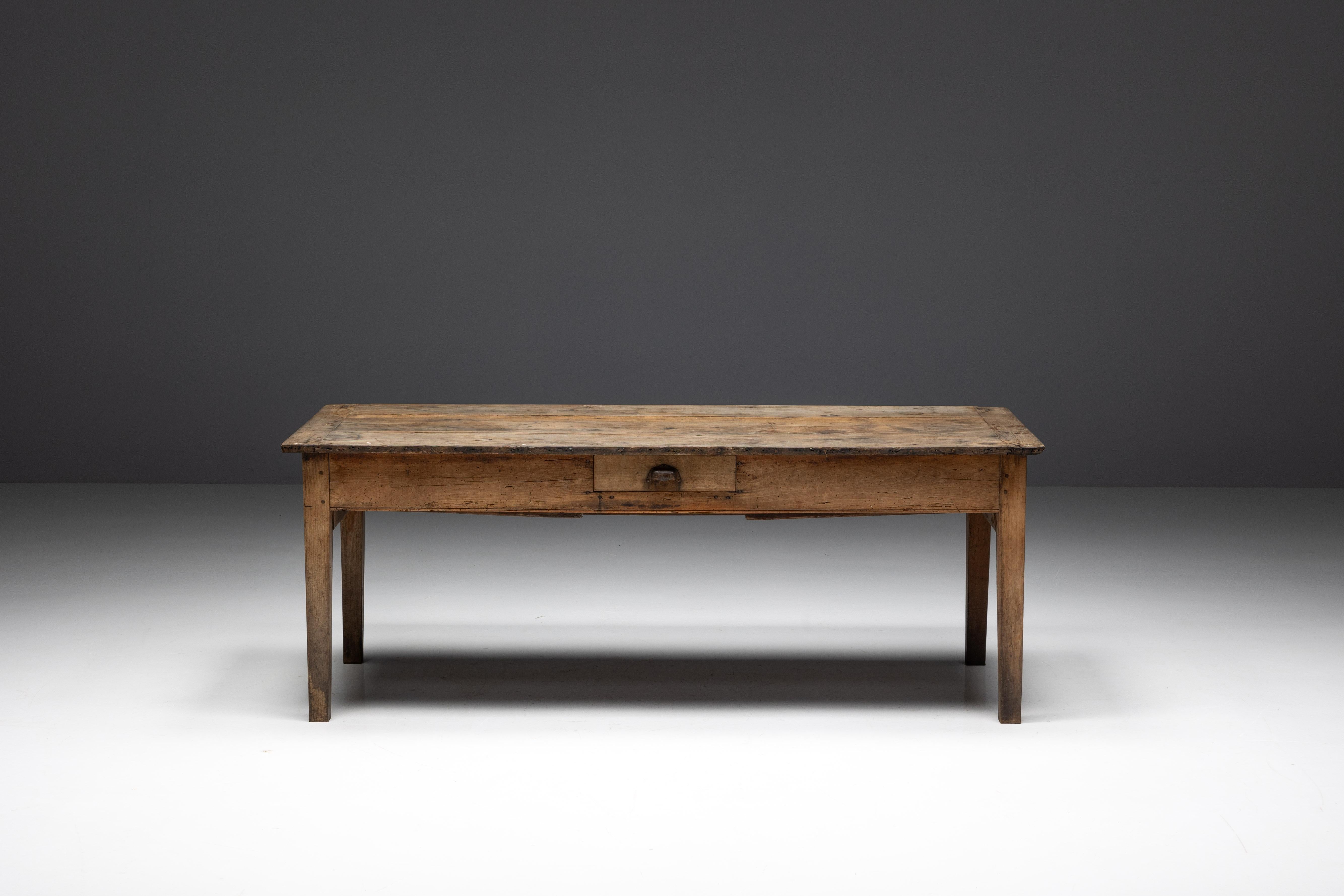 Mesa de granja francesa del siglo XIX, impregnada de la tradición artesanal del art populaire de la Francia rural. Esta pieza única cuenta con cajones de generosas dimensiones a cada lado, que ofrecen un amplio espacio de almacenamiento para objetos