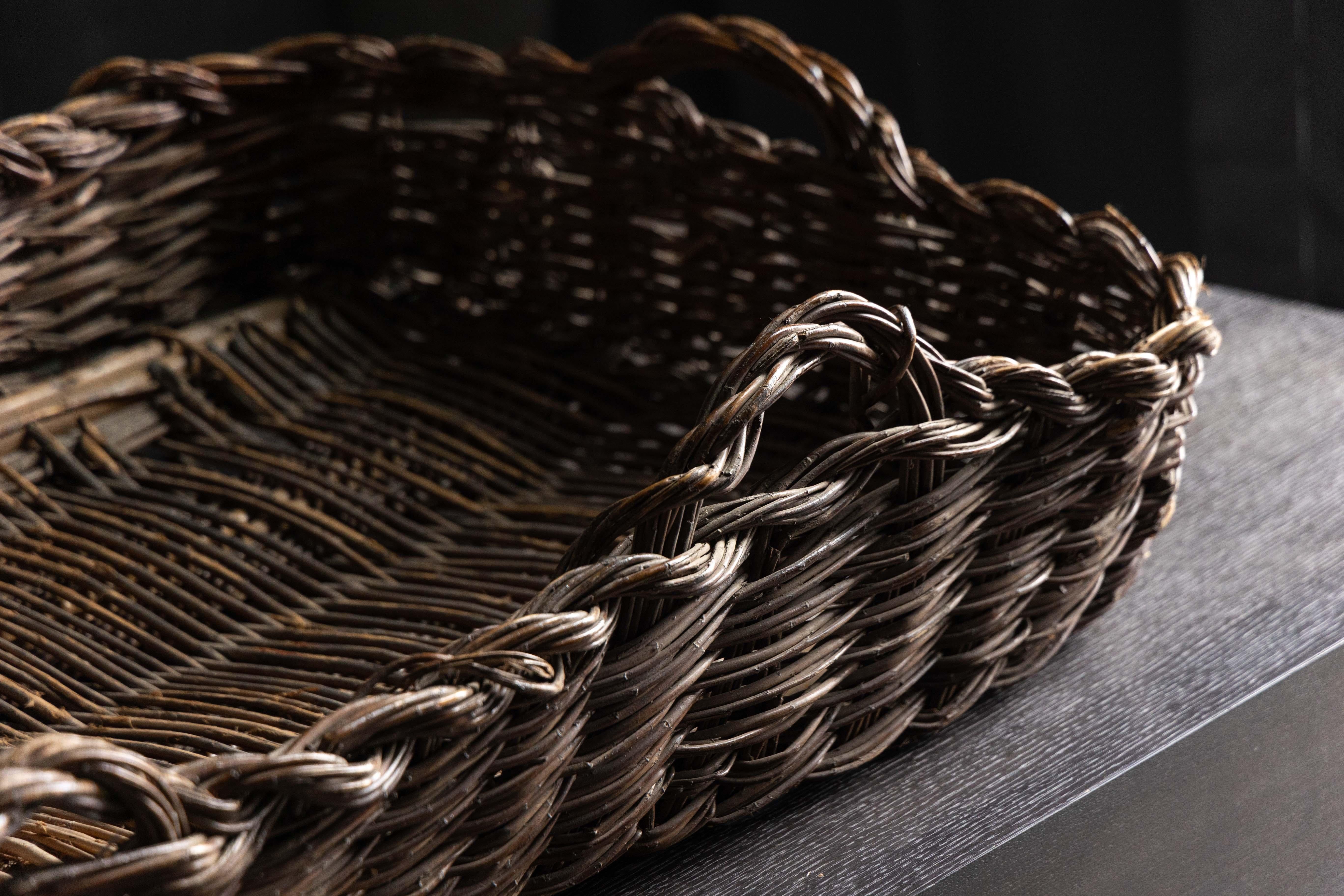 Questo grande cesto di vimini del XIX secolo è un ottimo esempio di artigianato tradizionale. Intrecciata a mano con fibre naturali resistenti, la sua forma allungata e la struttura a trama aperta suggeriscono che in origine veniva utilizzata come