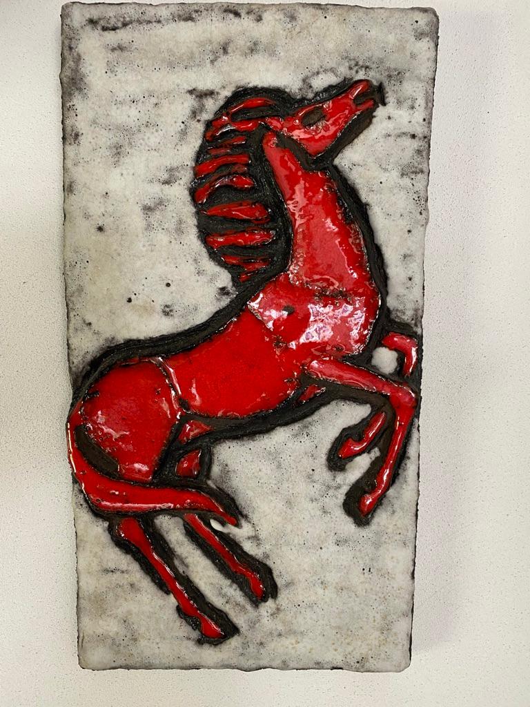 A huge and hard to get vertical wall plaque by RUSCHA KERAMIK, series Vulcano with horse decor. This rare version is manufactured in red/brown clay, white and brown fat lava background and red glazed horse.
The plaque is depicting a rearing horse.