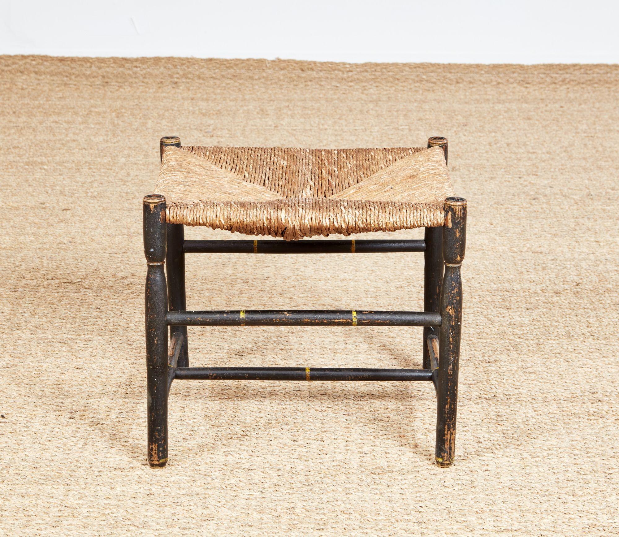 Sgabello inglese del XIX secolo con seduta in giunco su una struttura in legno chiaro tornito che presenta due barelle superiori tornite e sopra barelle inferiori a forma di H che uniscono quattro gambe sagomate tornite, il tutto con vernice nera