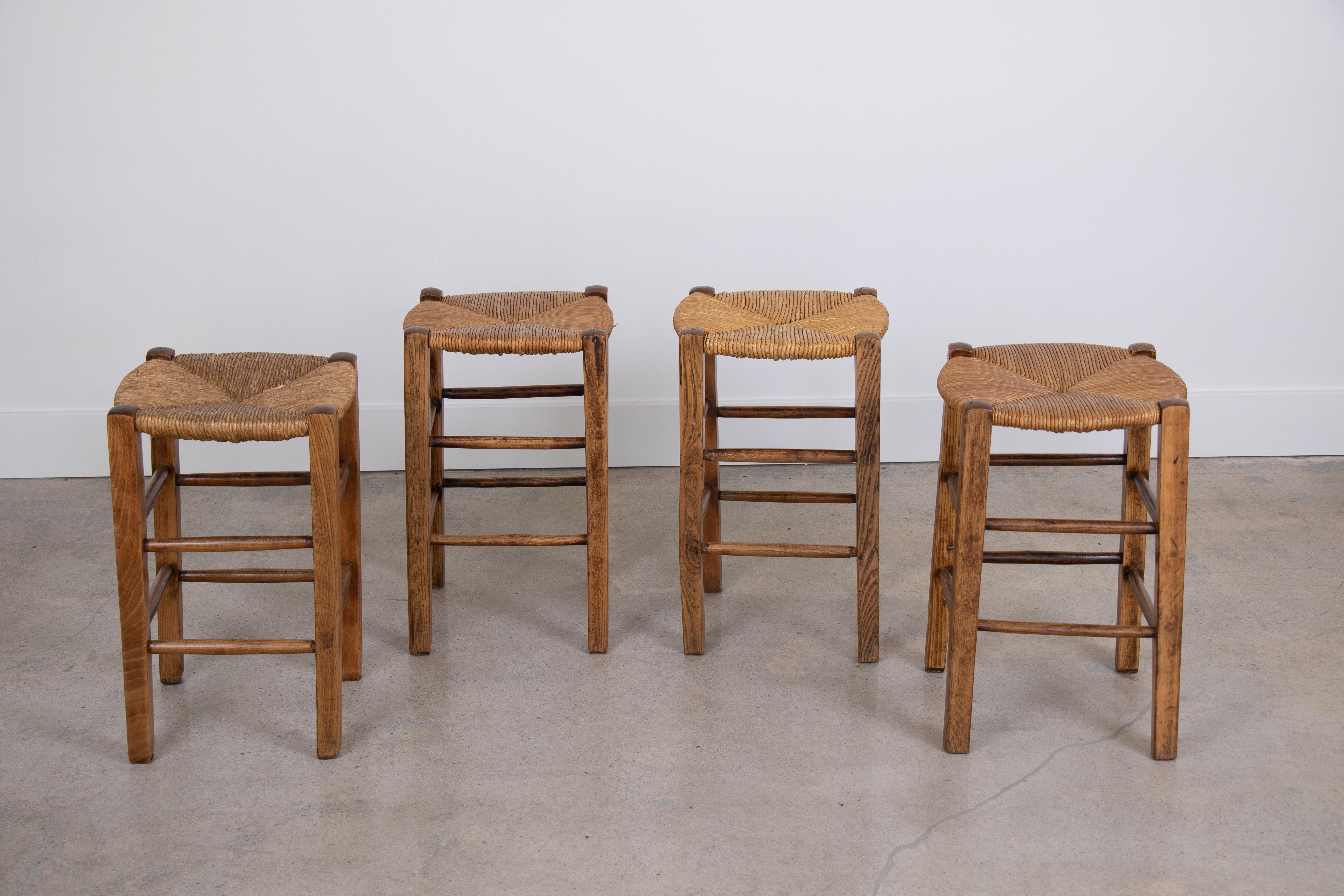 French wood and woven rush stools in the style of Charlotte Perriand. Four available and sold in sets of two.