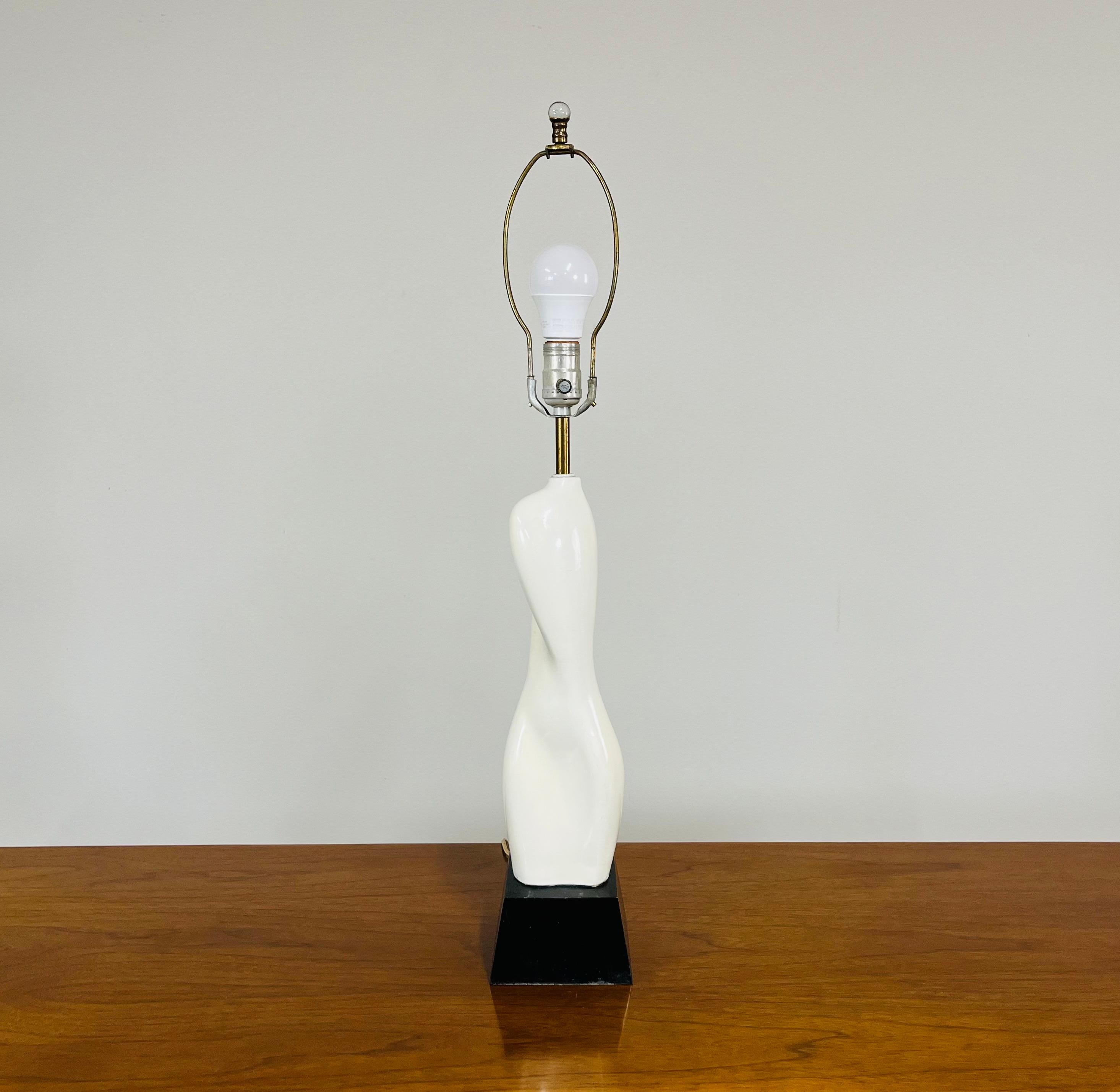 Cette lampe sculpturale au design élégant représente une forme féminine nue en train de tourner, conçue par Russel Wright. Céramique avec base en bois tourné et quincaillerie en laiton. En excellent état vintage, sans aucun dommage. Le câblage