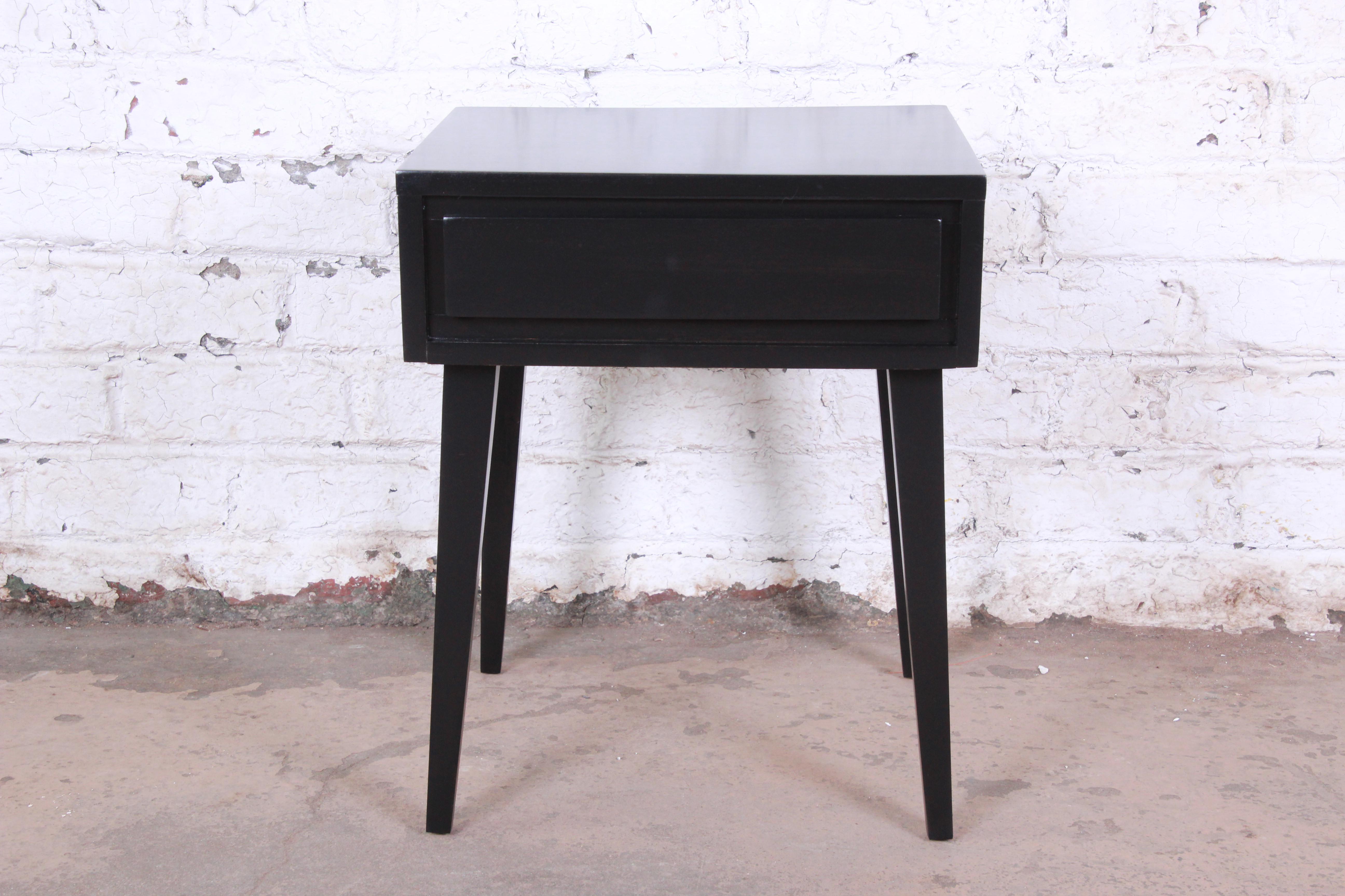 An exceptional Mid-Century Modern ebonized nightstand or end table designed by Russel Wright for his American Modern line for Conant Ball. The nightstand features solid birch wood construction, with sleek, Minimalist Mid-Century Modern design. The