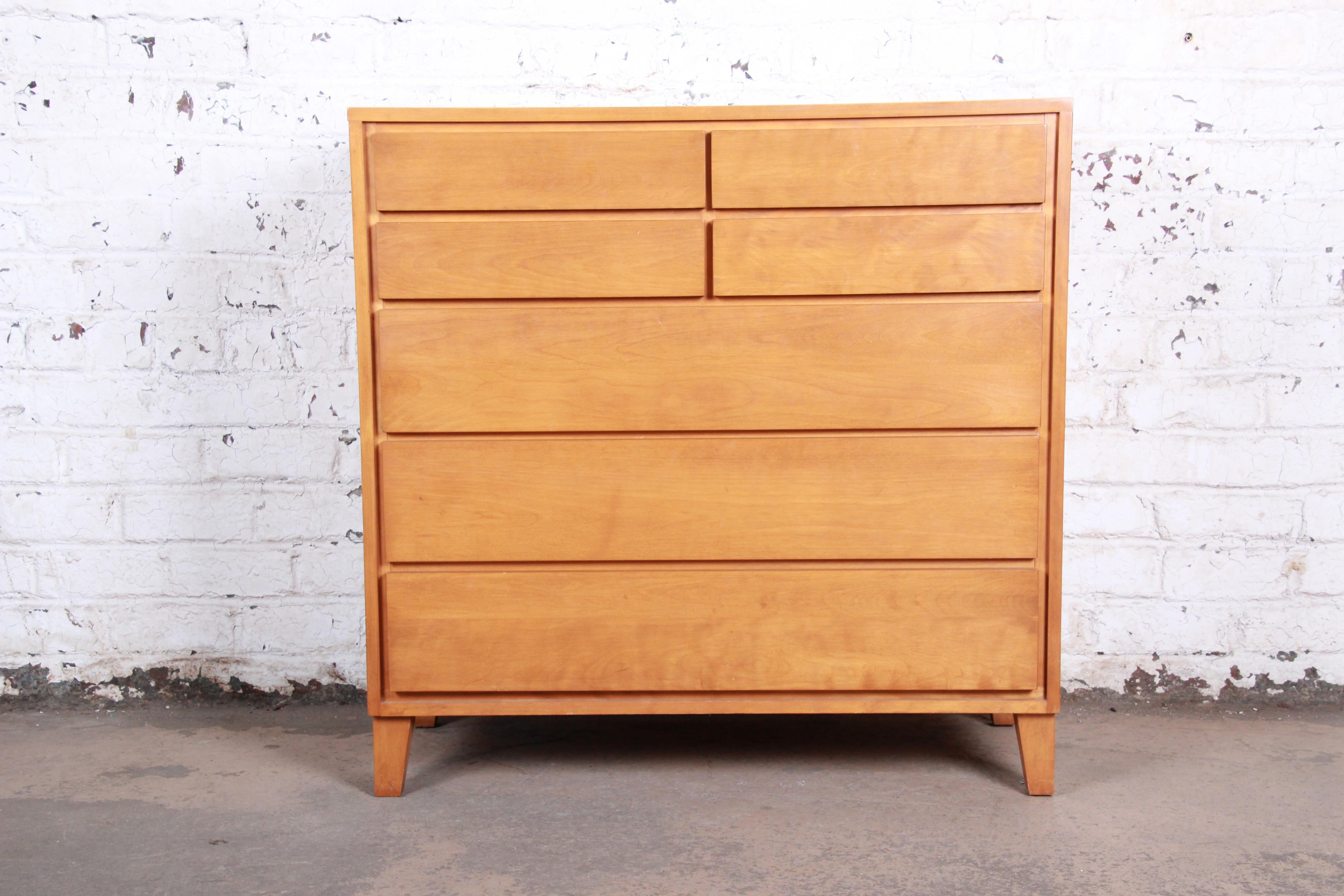 A gorgeous American Modern highboy dresser designed by Russel Wright for Conant Ball, circa 1950. The dresser features solid maple construction with beautiful wood grain and sleek, minimalist mid-century design. It offers ample storage, with seven
