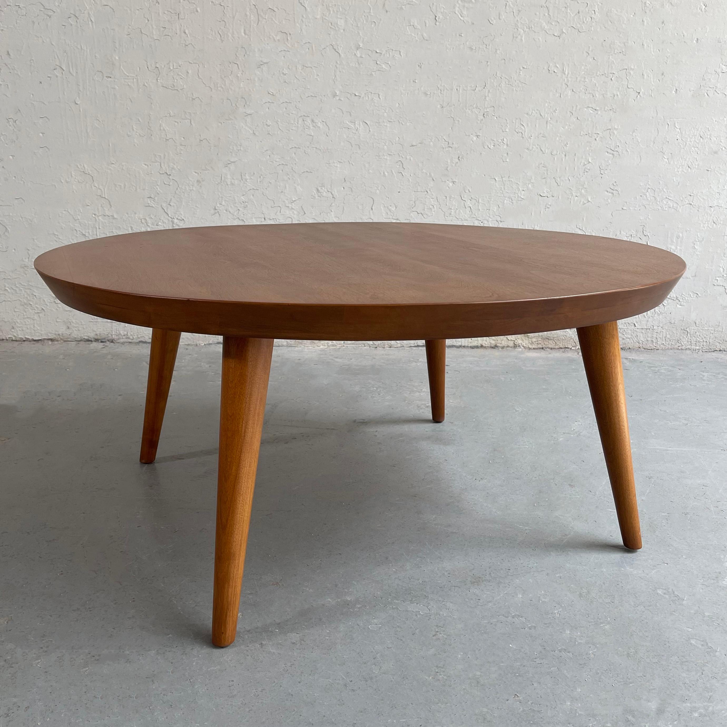 Streamlined and elegant, Mid-Century Modern, round ash coffee table by Russel Wright for Conant Ball features a beveled edge and tapered legs.
