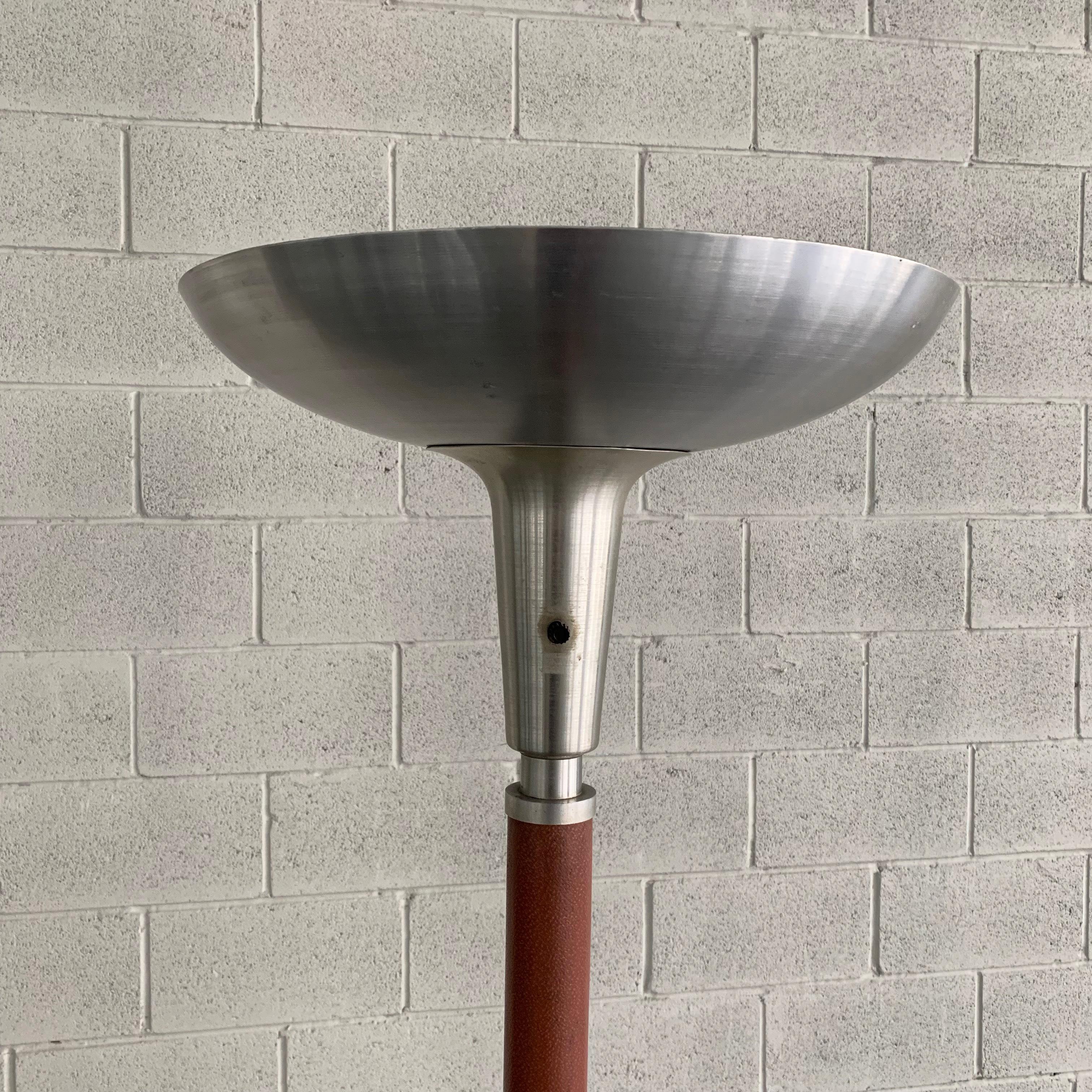 Midcentury, machine-age, torchiere floor lamp by Russel Wright is spun aluminum with a luggage tan leather clad stem. The lamp accepts a single, three-way. Mogul size bulb up to 300 watts. A medium socket adapter can be included to use a regular