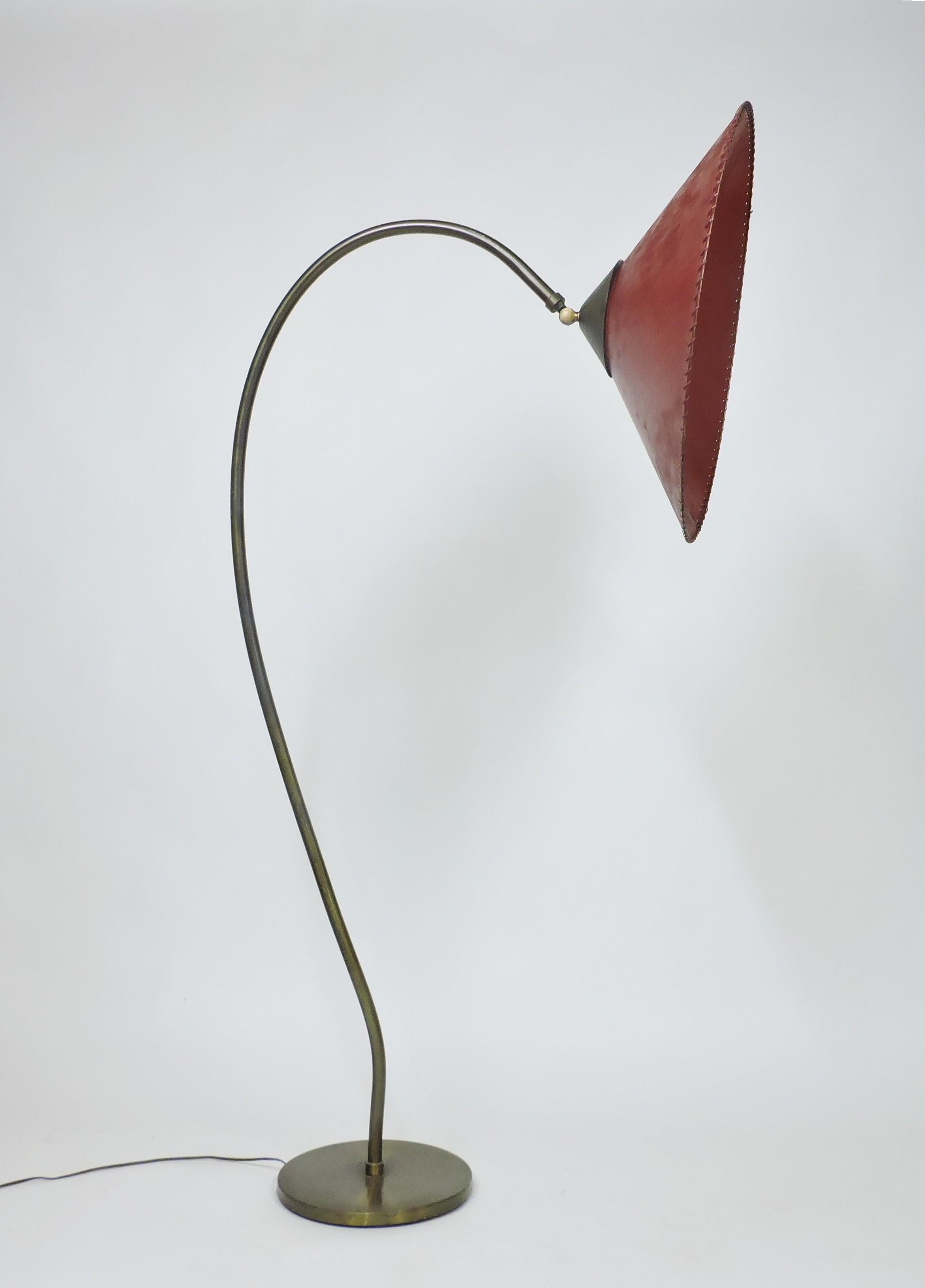 Grande e imponente lampada da terra della metà del secolo nello stile di Russel Wright. Questa lampada ha un grande paralume in pergamena di vetro rosso a forma di cono con uno stelo in ottone curvo e una base rotonda. Il paralume da 24 pollici di