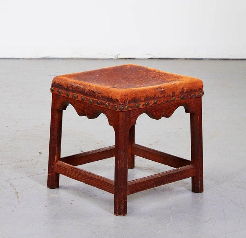 The Russell stool, one of Gordon Russell's earliest and most successful Cotswold School designs, featuring pegged construction with an upholstered seat over chamfered splayed legs and stretchers, the aprons with Cupid's bow scalloping. This stool