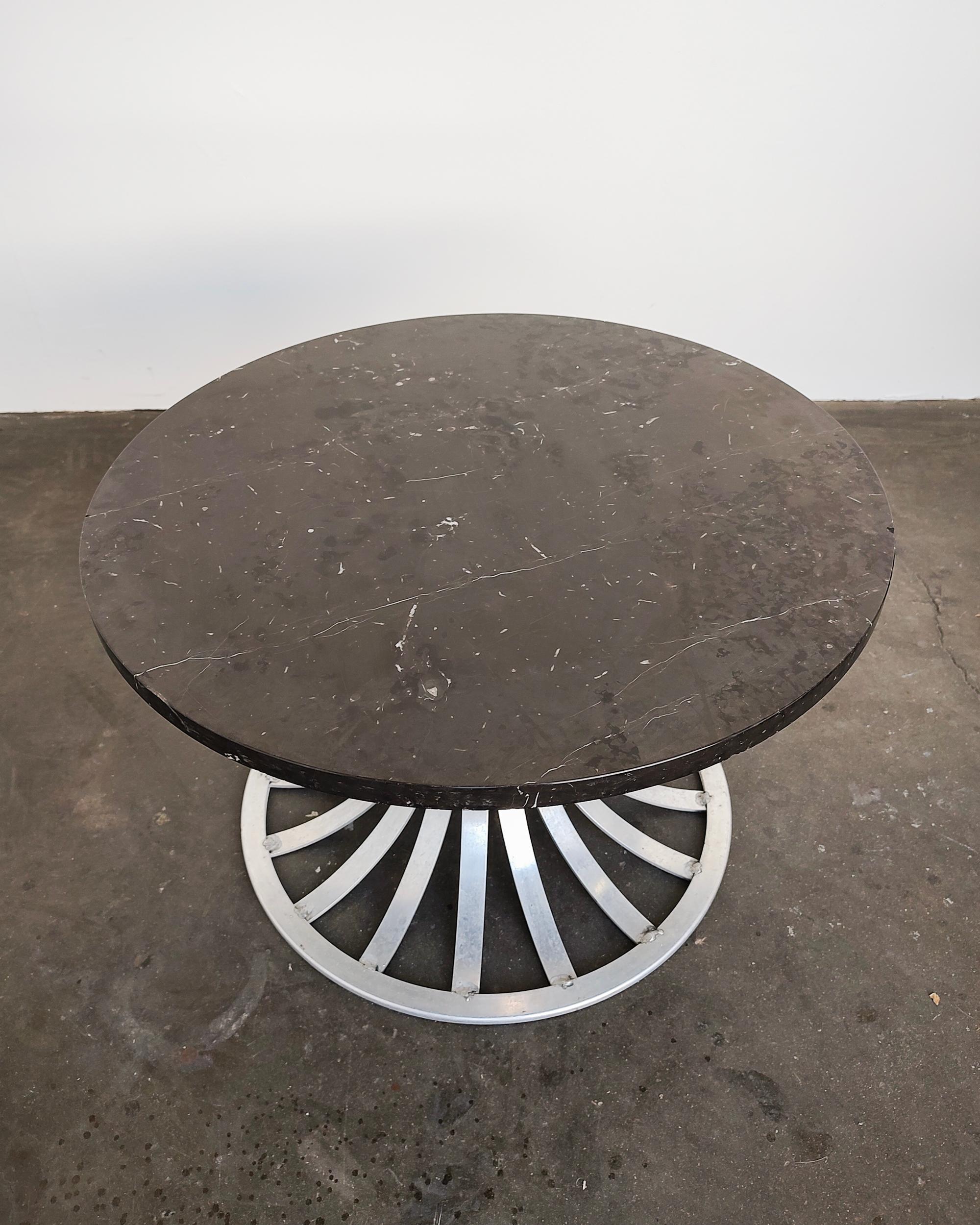Russell Woodard aluminum base tulip coffee table. Round dark marble top with light white veining sits without hardware on aluminum base. Overall great vintage condition, some light wear present, small chip on marble edge, hairline crack in aluminum