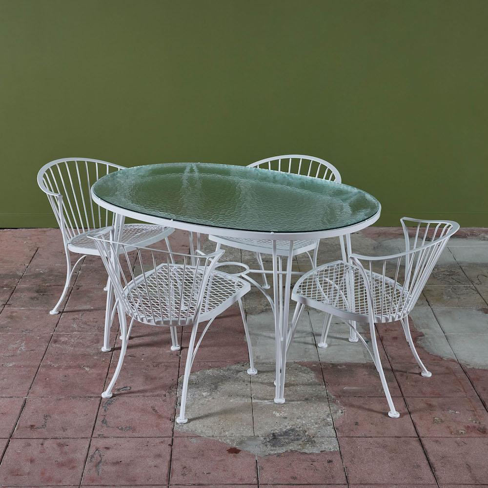 Essgarnitur für den Außenbereich von Russell Woodard für Woodard Furniture, ca. 1950er Jahre. Das Pinecrest-Set besteht aus vier schmiedeeisernen Beistellstühlen und einem ovalen Tisch mit Glasplatte. An der Unterseite des Tisches befinden sich auf