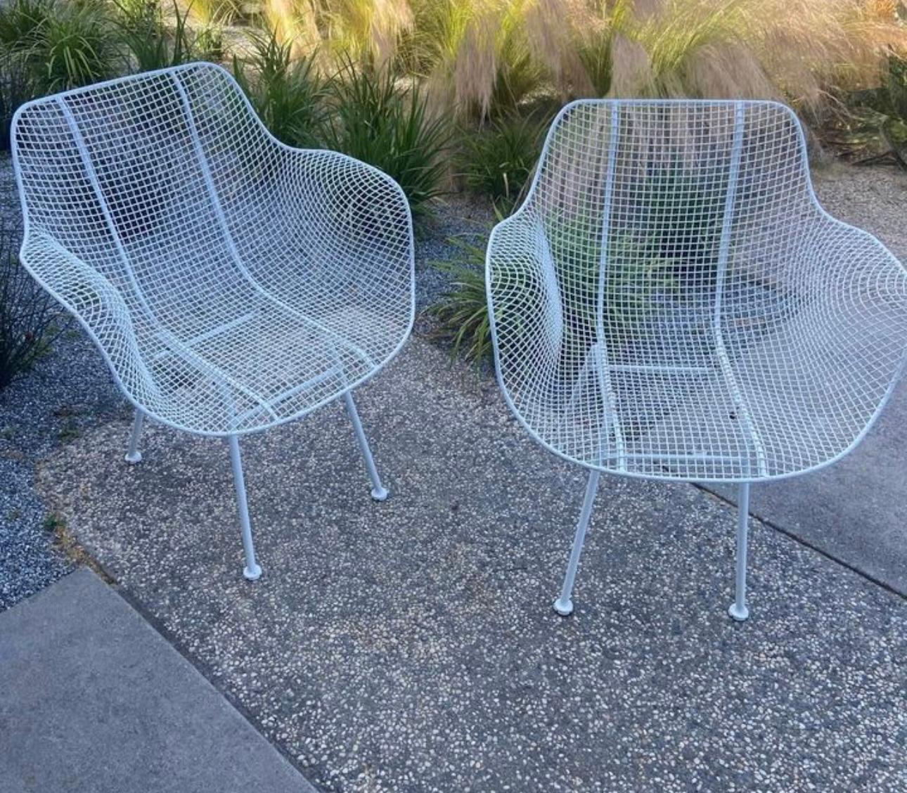 Pair of original Woodard Sculptura armchairs. A versatile option for outdoor entertaining, or indoors, this set is dining chair height so can be used with a patio table. The wrought iron frames and woven mesh steel seats are strong and can stand all