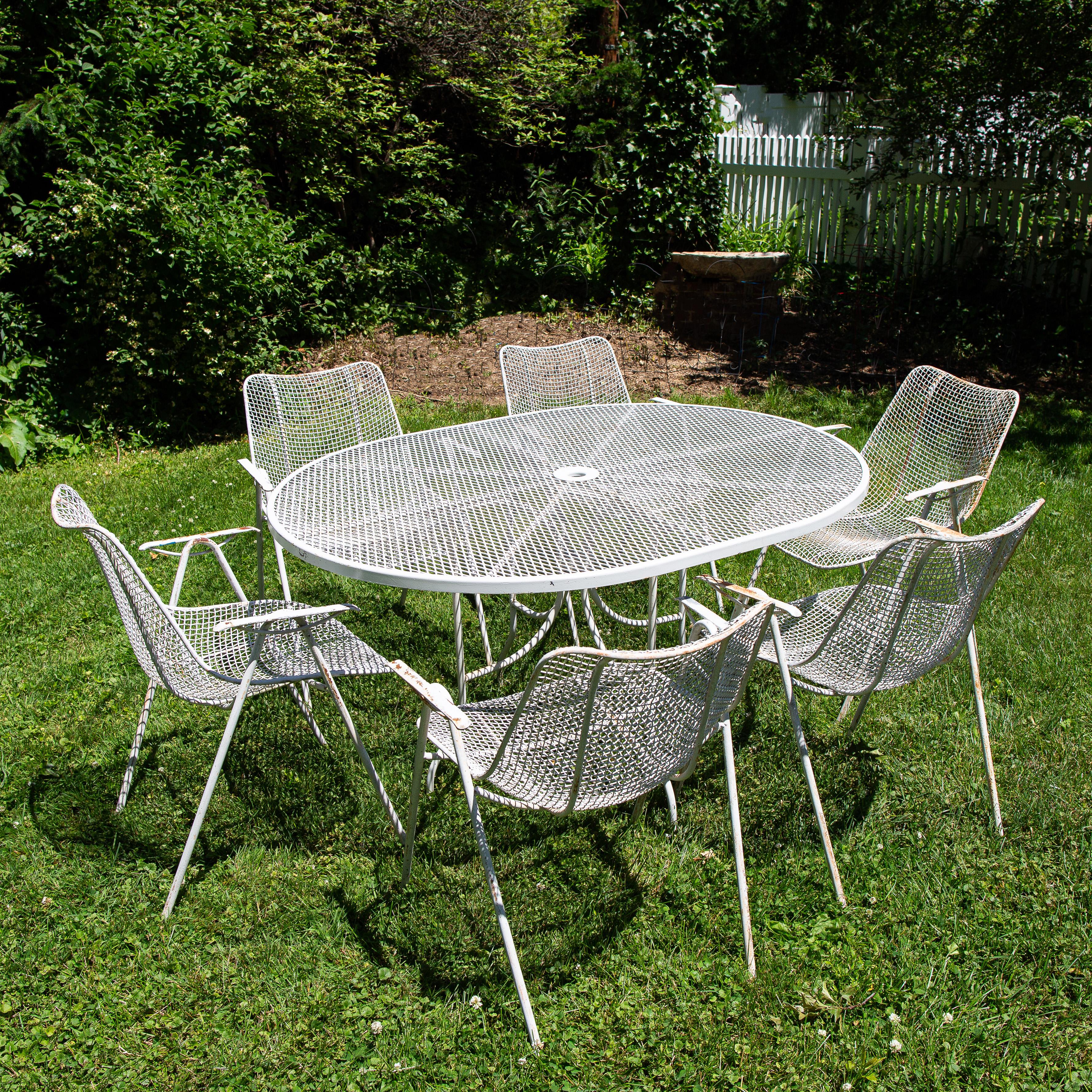 Mid-Century Modern, steel mesh and wrought iron, outdoor, patio dining set by Russell Woodard, Sculptura features 6 armchairs with an oval dining table. The chairs measure: 24 width x 24 depth x 32 height, seat height 17. The table measures: 54 x 42