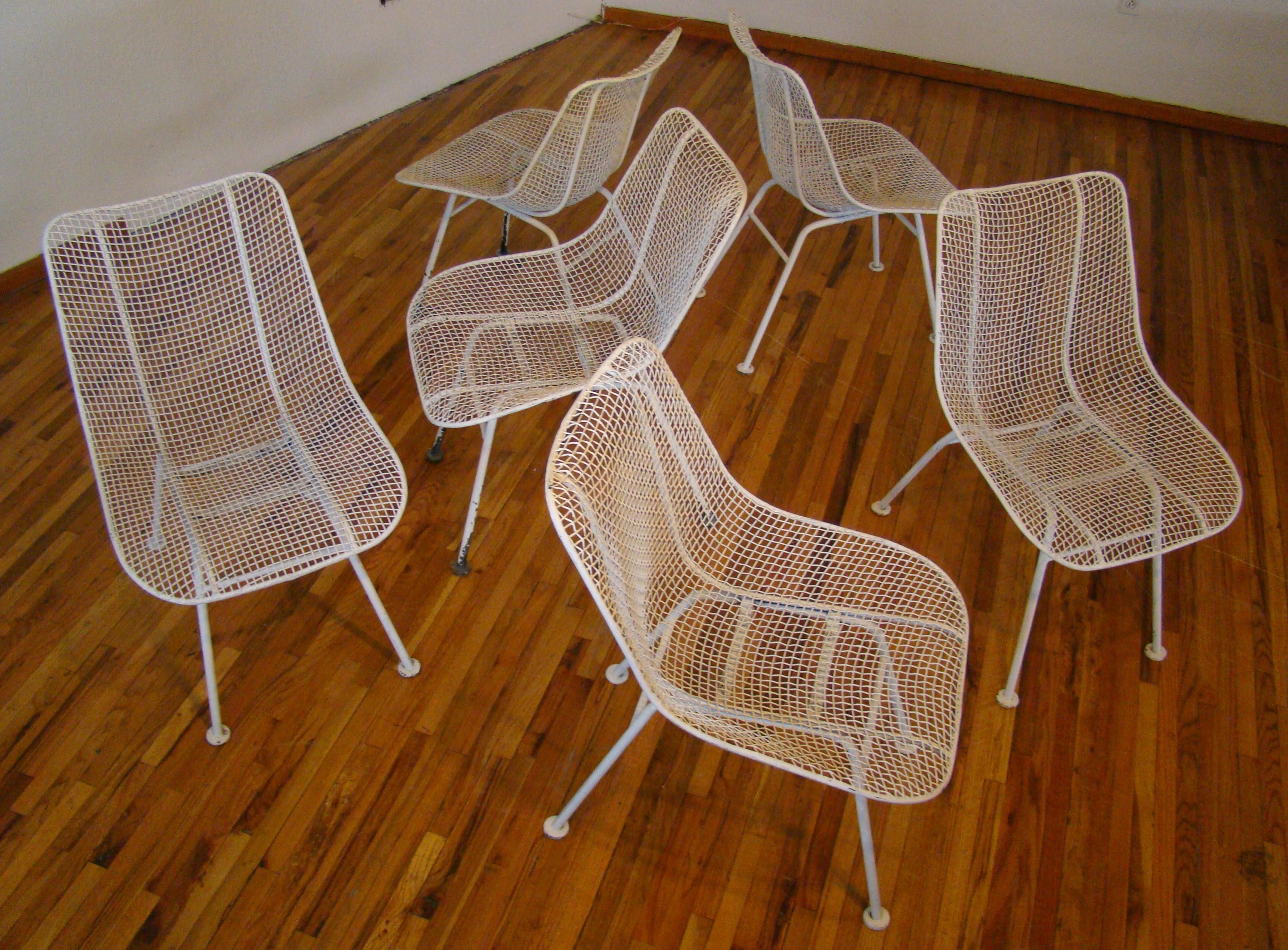 Outdoor dining chairs by Russell Woodard for Woodard Furniture, c.1950s. The side chairs are from Woodard’s “Sculptura” line designed in 1956. Each chair has a molded mesh frame that sits atop four wrought iron legs with disc feet. The chairs need
