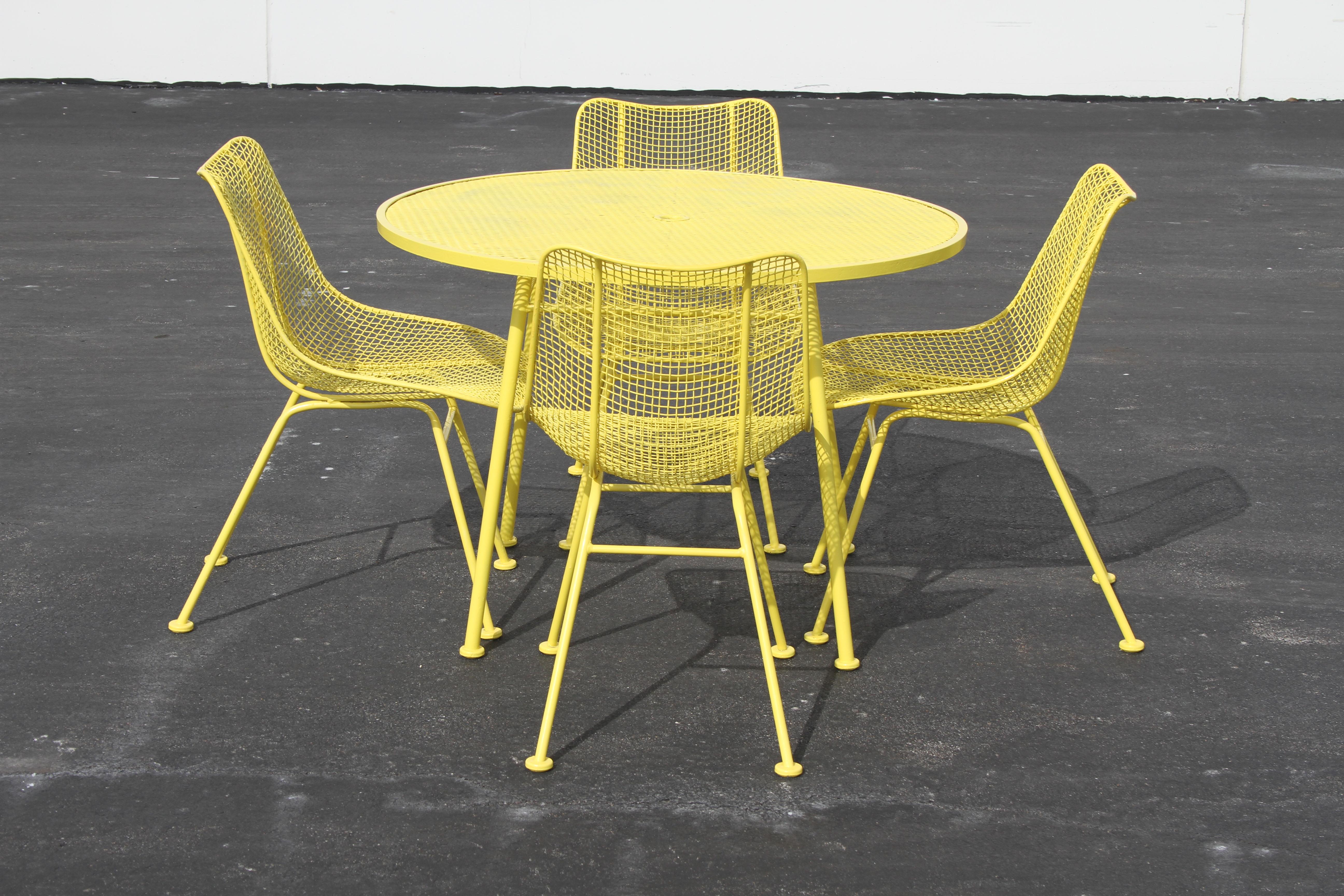 Russell Woodard midcentury Sculptura patio set with 4 side chairs and round table with umbrella hole. From one owner estate, who kept the set indoors in the winters. Older pop yellow paint, some chips, few paint runs and flakes. It can be