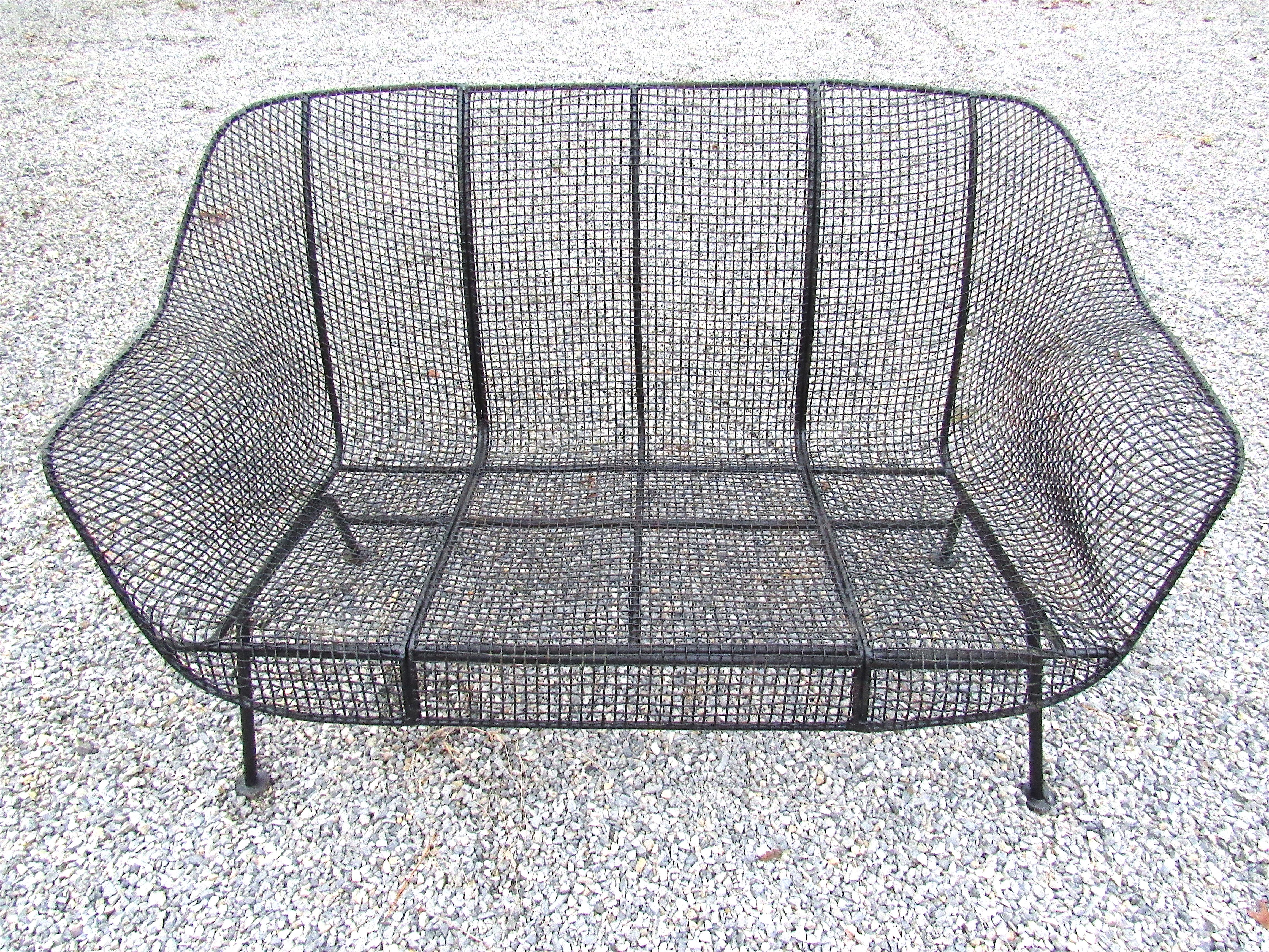 Beautiful midcentury patio set by Russell Woodard. Signature design with a wrought iron frame and wire mesh seating. Stylish set sure to make an impression. This set contains two armchairs, one settee, and 3 end tables. Suitable for both indoor and