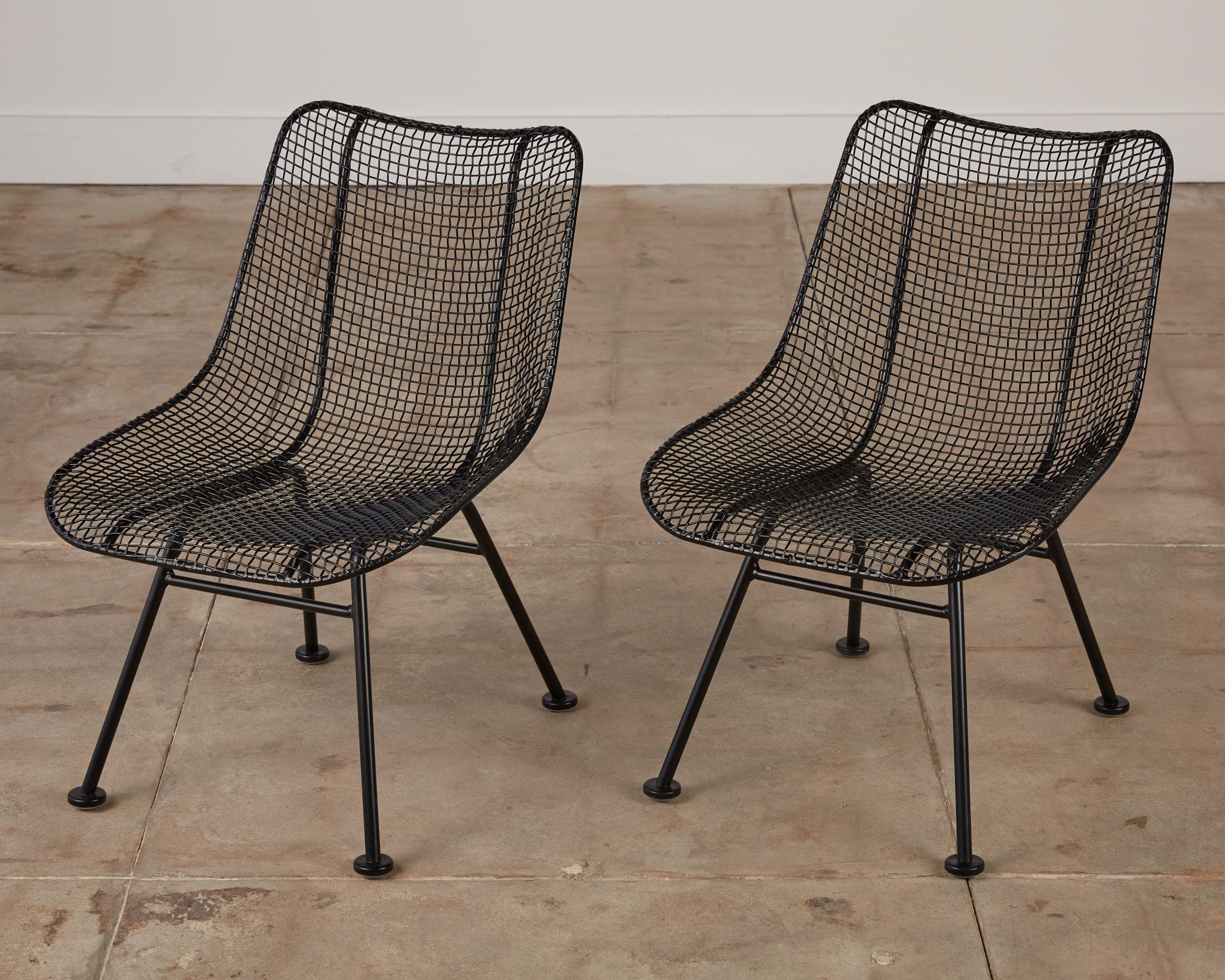 Outdoor dining chairs by Russell Woodard for Woodard Furniture, c.1950s. The side chairs are from Woodard’s “Sculptura” line designed in 1956. Each chair has a molded mesh frame that sits atop four wrought iron legs with disc feet. The chairs have