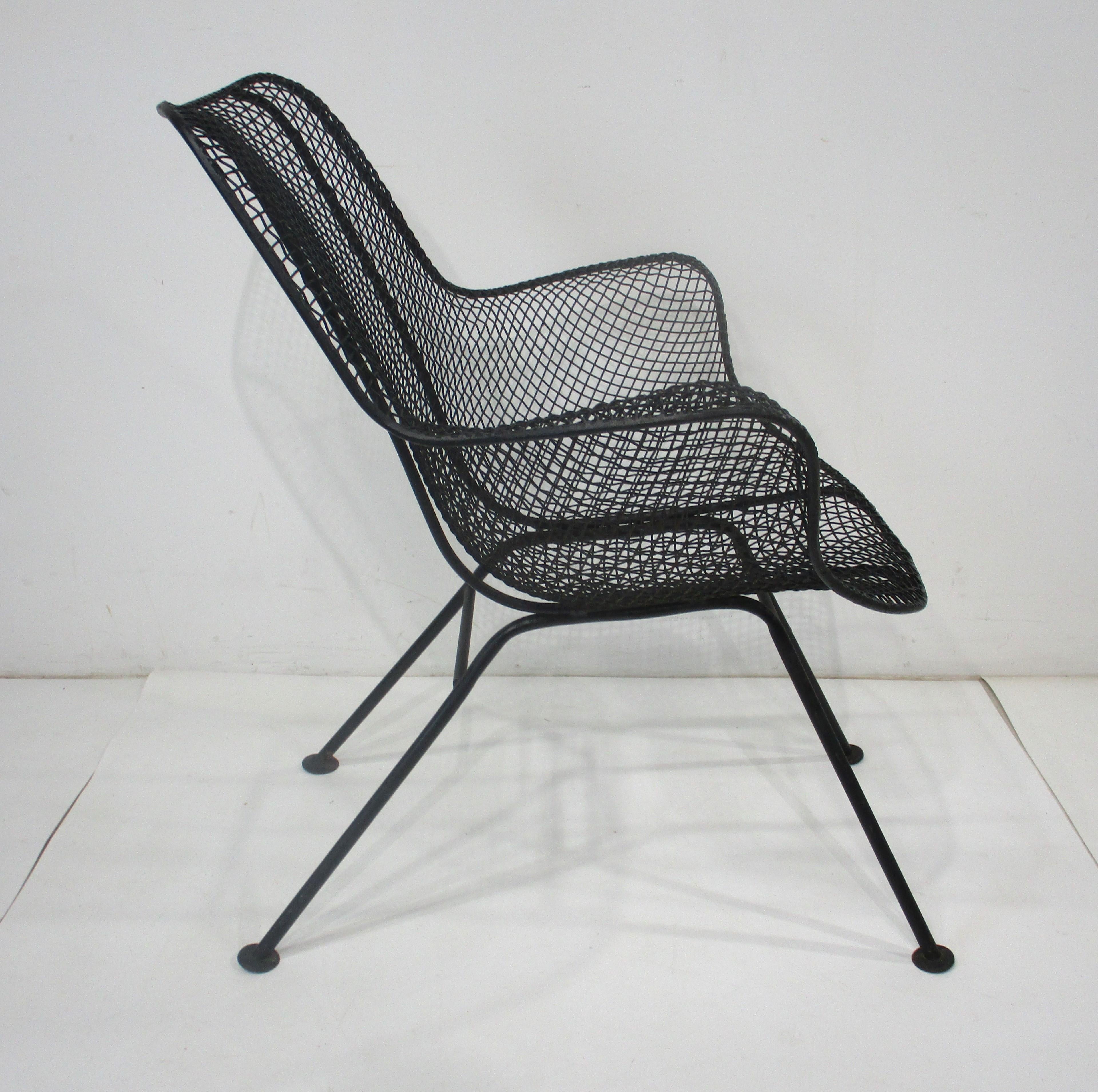 A wire and iron molded and welded Sculptura armchair in the style of Eames with foot pads and in a satin black finish. Great for a three seasons room, deck, porch or that cozy garden, super comfortable manufactured by the Woodard Furniture Company