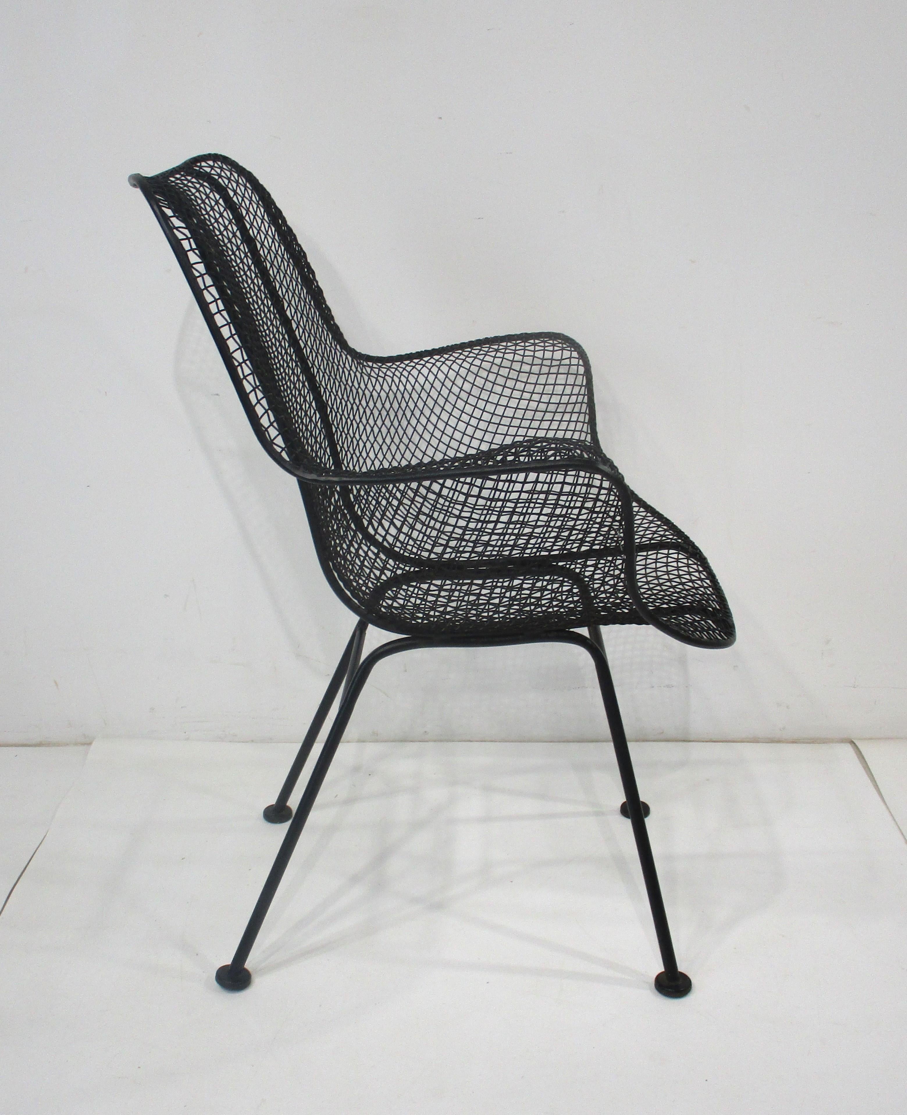 A wire and iron molded and welded Sculptura armchair in the style of Eames with foot pads and in a satin black finish. Great for a three seasons room, deck, porch or that cozy garden, super comfortable manufactured by the Woodard Furniture Company
