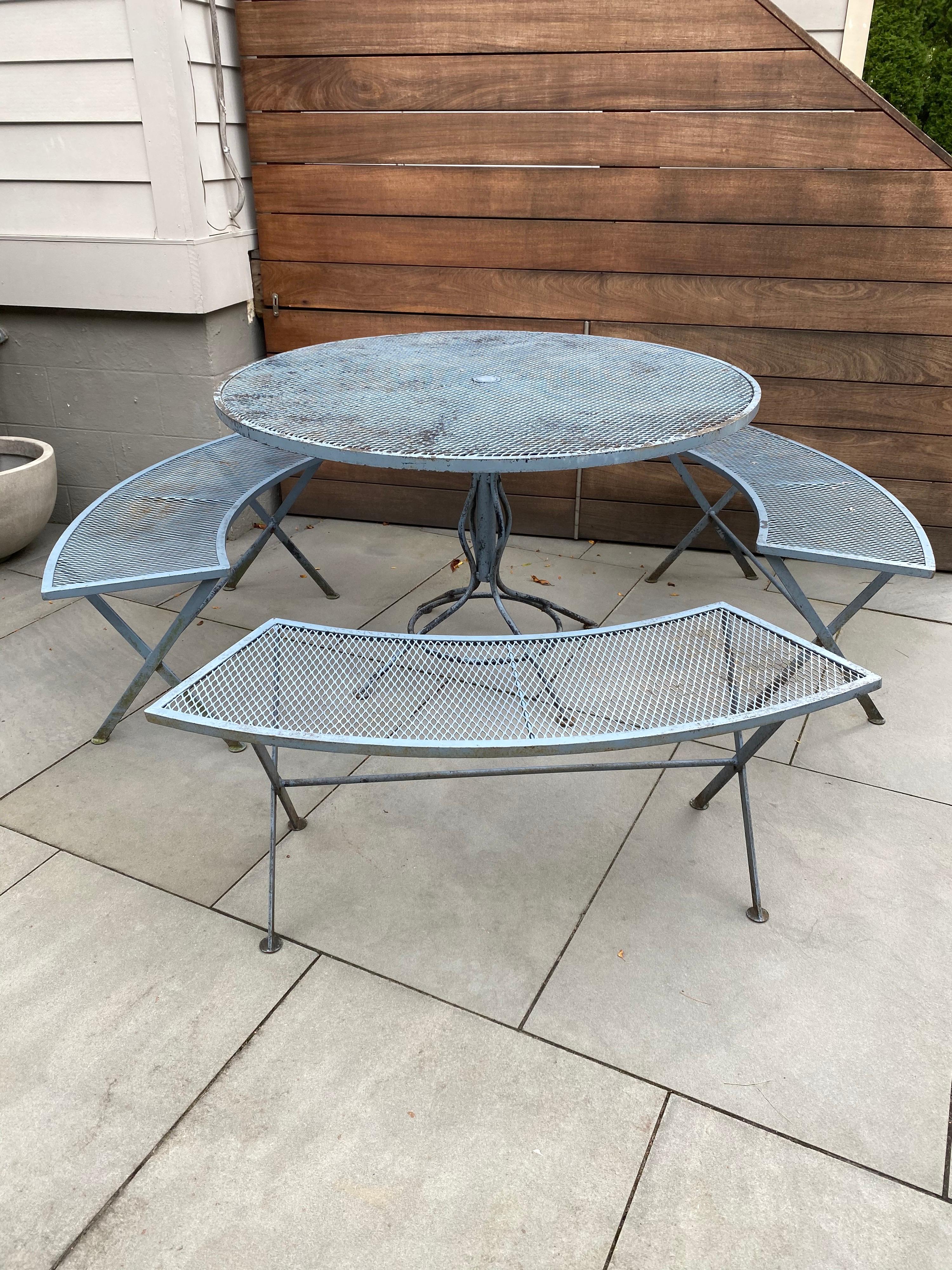 Nice Russell Woodard iron table and 3 curved benches. Set has a slightly worn blue gray paint finish. Table is 47'5 round and 29