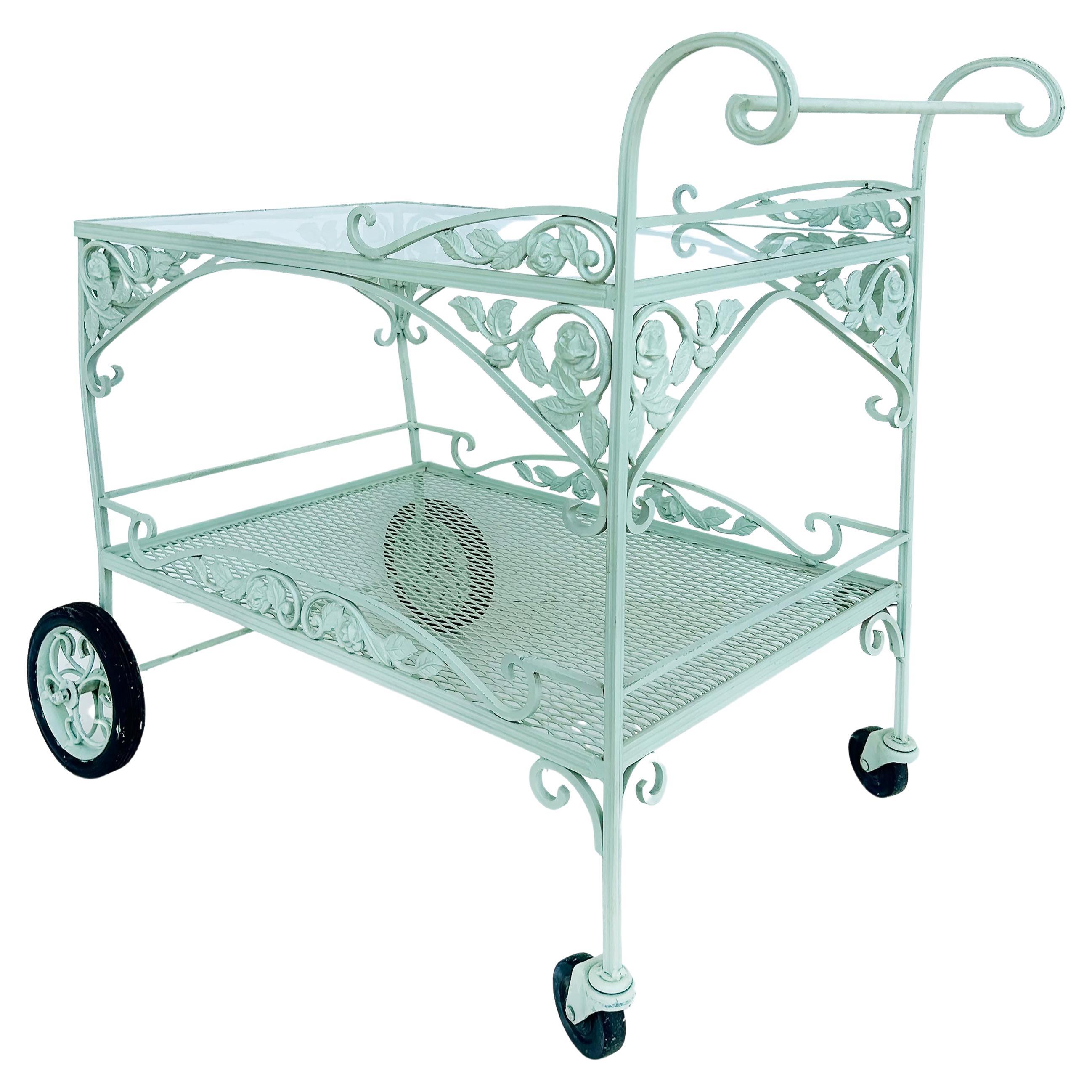 Russell Woodard Wrought Iron Patio/Serving/Bar/Tea Cart With Floral Decoration

Offered for sale is a Russell Woodard painted wrought iron and glass patio/garden/pool serving cart with a glass top and raised on rubber wheels.  The matching table and