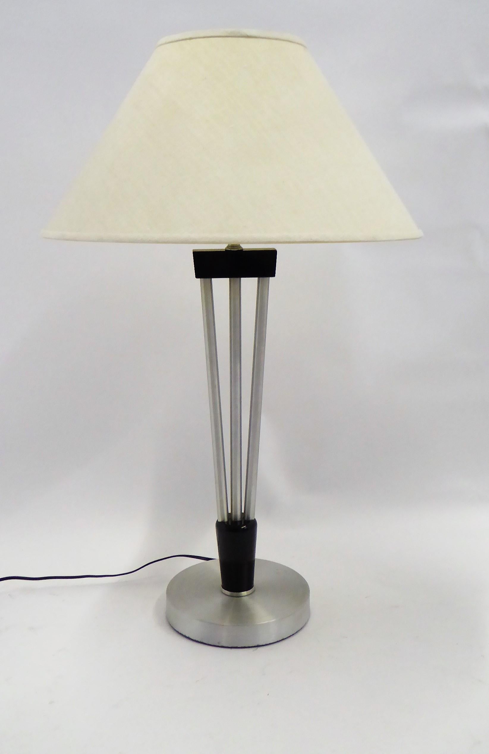 Wonderful late 1940s table lamp by Russel Wright. The socle base of circular spun aluminum topped by an ebonized carved wood base to three up climbing aluminum poles to an ebonized wood shoulder continuing to a neck socket holding the milk glass