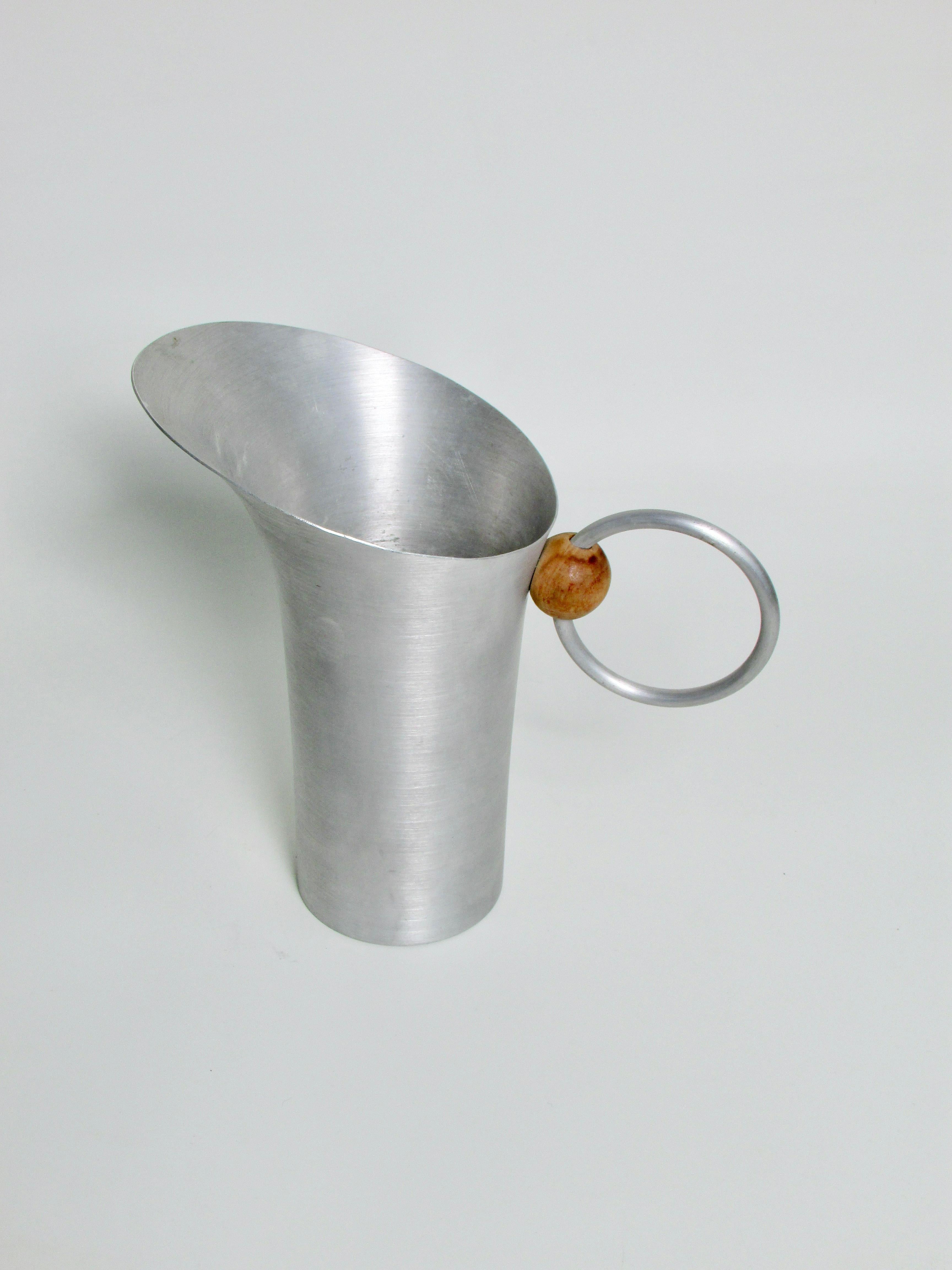 More sculpture than utilitarian object . Water or drinks pitcher . Nicely proportioned with aluminum ring handle through wood ball . Designed by  one of the leading mid century industrial designers Russel Wright . From his spun aluminum series .