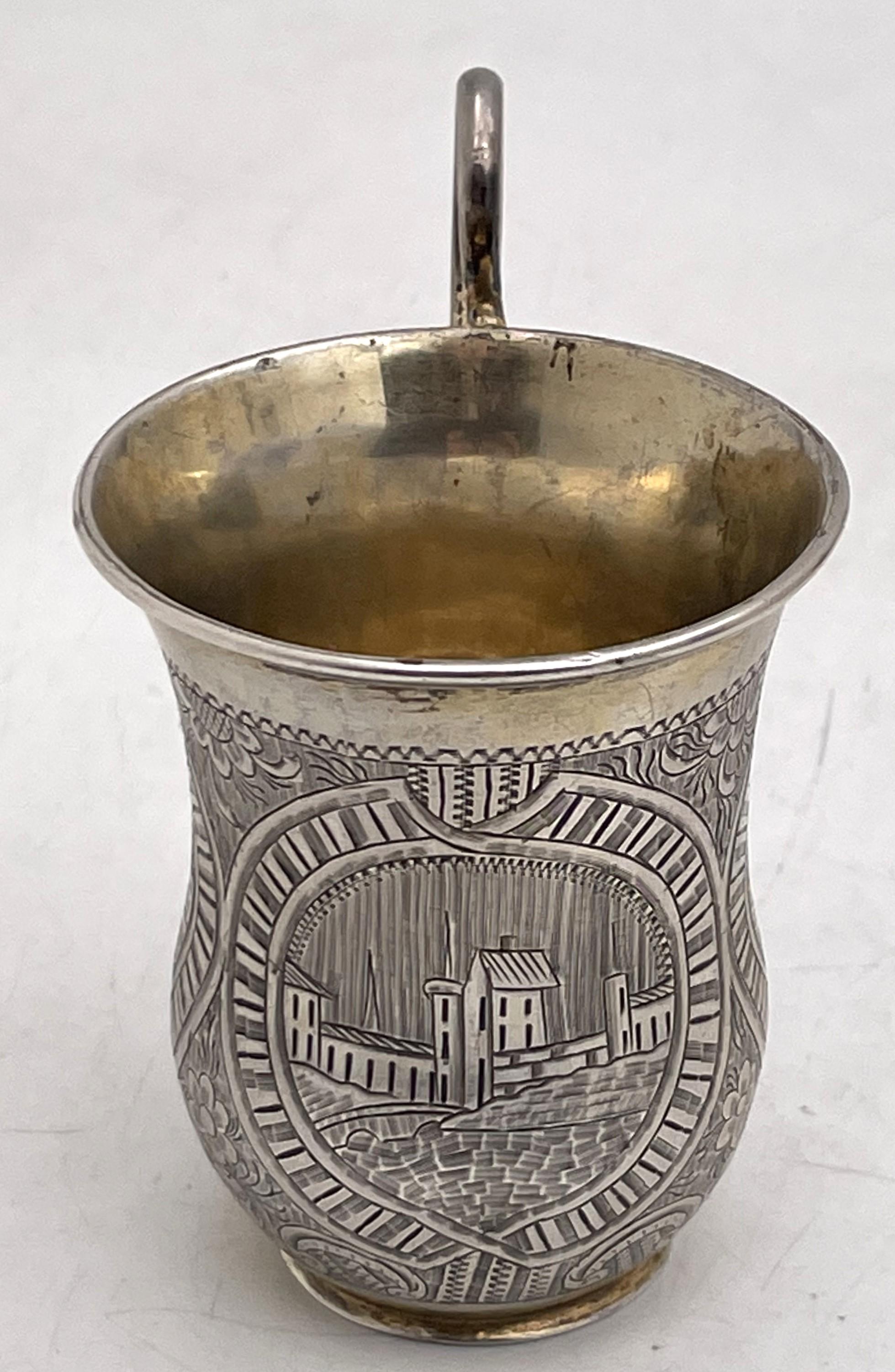 Russian 0.84 silver, partially gilt, vodka mug, made in Saint Petersburg in 1851, showcasing stylized floral and architectural motifs. It measures 3 1/8'' in height by 2 1/8'' in diameter at the top and bear hallmarks as shown. 

Please feel free to