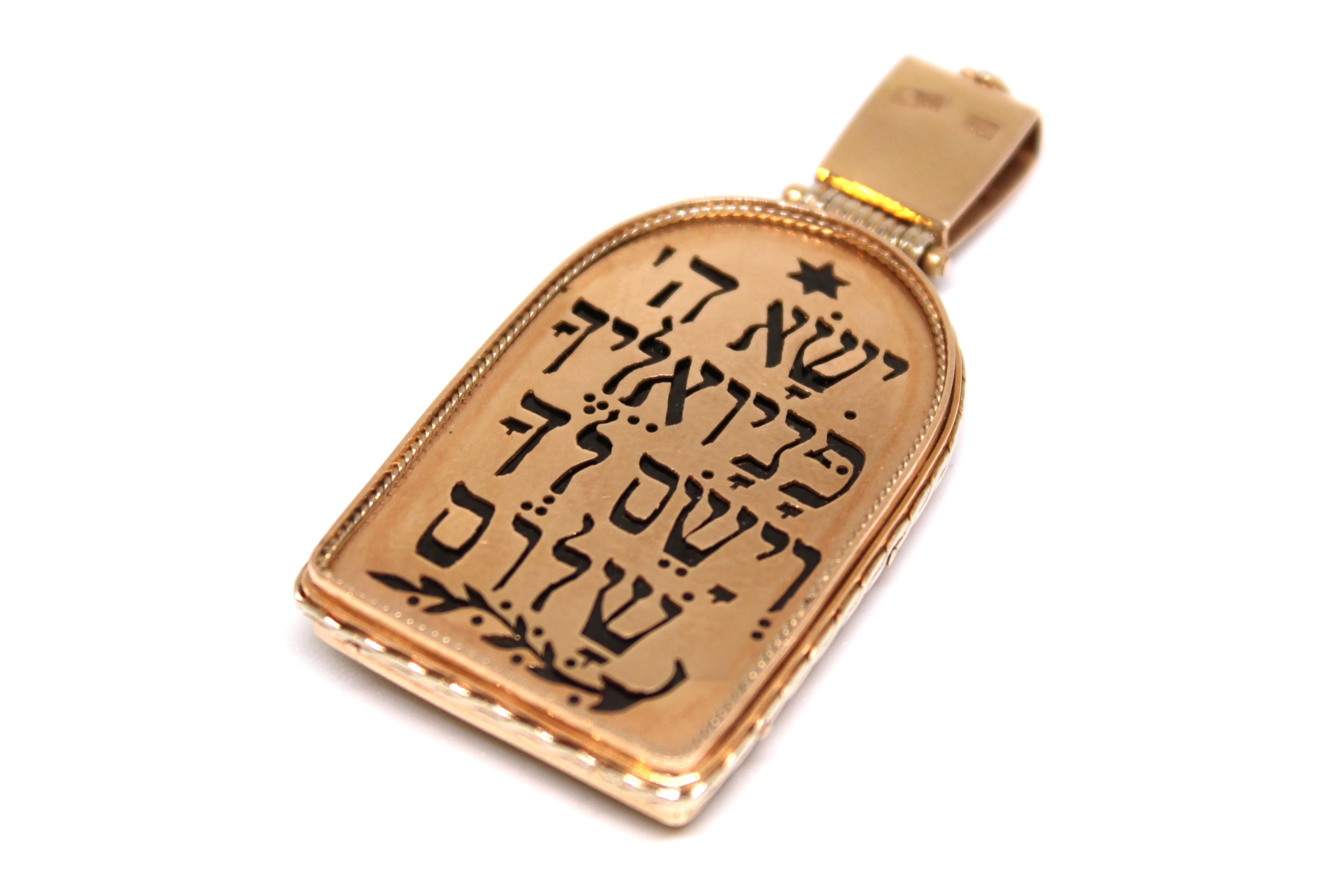 Questo straordinario amuleto bifronte, realizzato in oro giallo 14kt, è un capolavoro dell'oreficeria russa degli inizi del XX secolo.

Il corpo a forma di tavoletta dell'amuleto è cavo e racchiude al suo interno una sorprendente pietra nera. Il