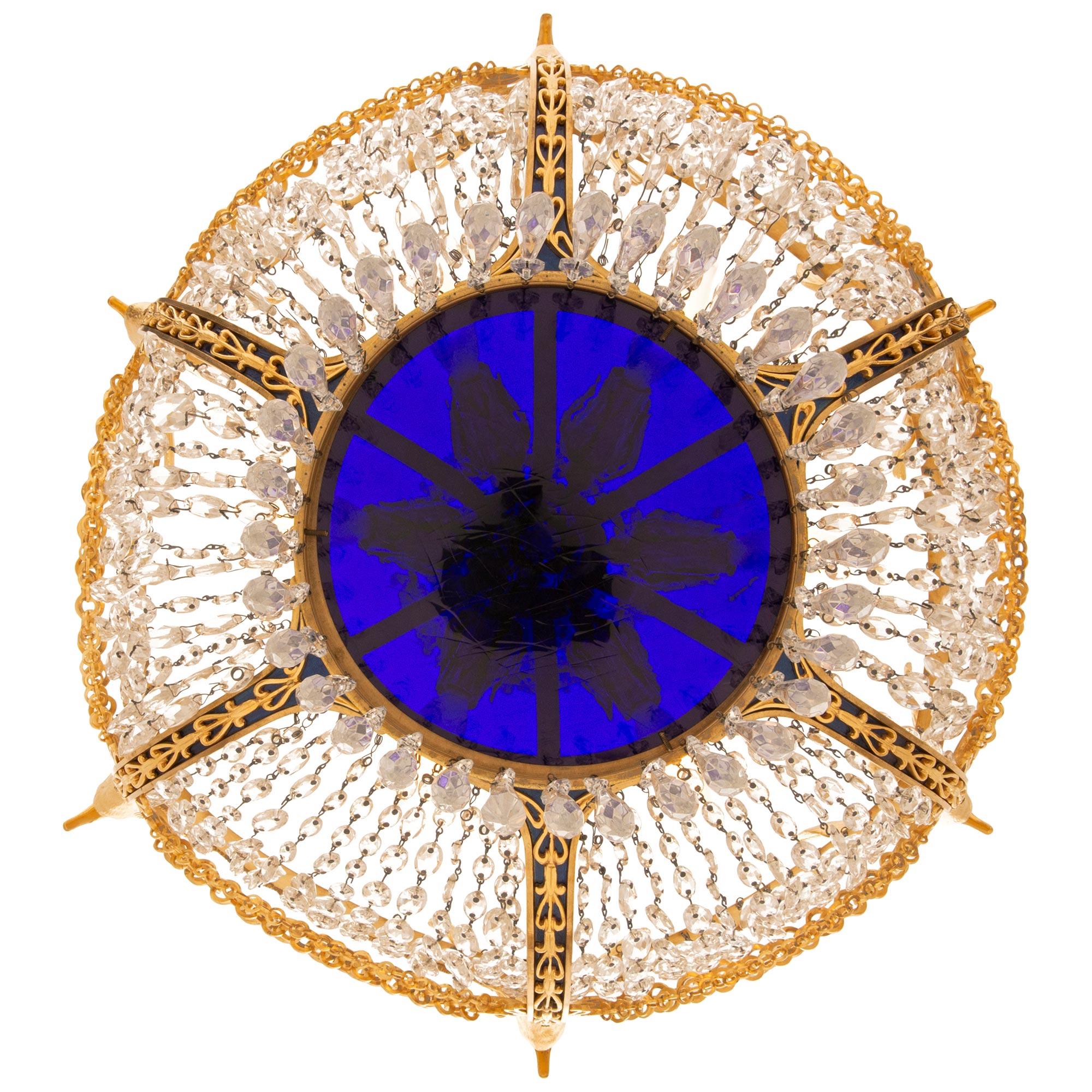 A stunning and highly detailed Russian 19th century Neo-Classical st. Crystal, Ormolu, enameled Bronze and Glass chandelier. This most decorative seven light chandelier is centered around a circular fitted cobalt blue glass tier with prism shaped