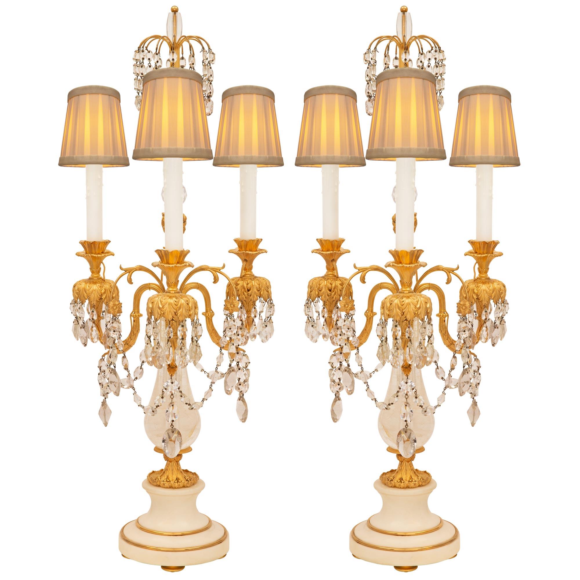 A stunning and extremely decorative Russian 19th century Neo-Classical st. white Carrara marble, rock crystal, crystal, and ormolu candelabra lamps. Each three arm lamp is raised by an elegant circular white Carrara marble base with a mottled