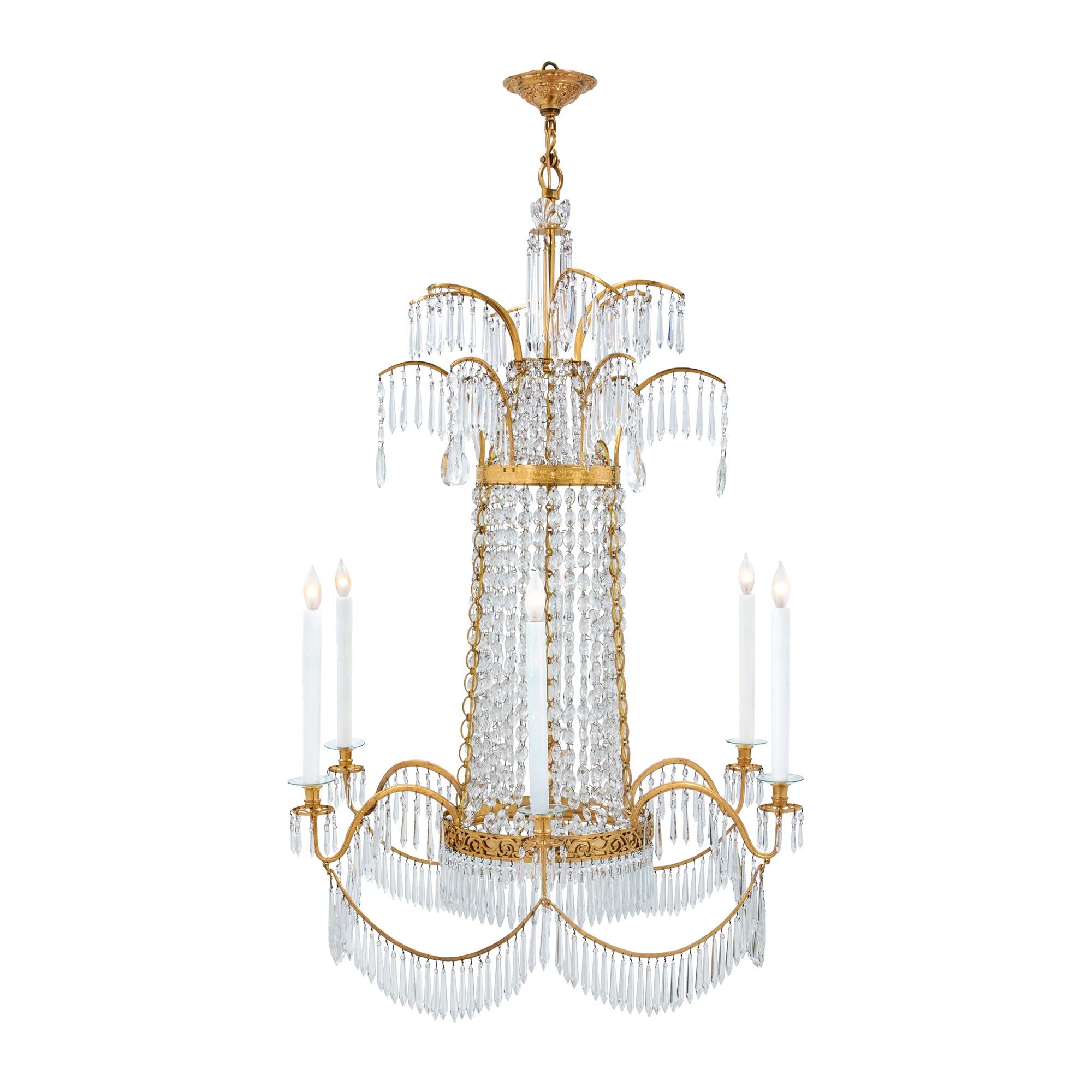 A stunning Russian 19th century Neo-Classical ormolu and crystal six light chandelier. The chandelier is centered by a beautiful bottom circular tier with a richly chased pierced, scrolled and foliate band. The ormolu back plate is adorned in prism