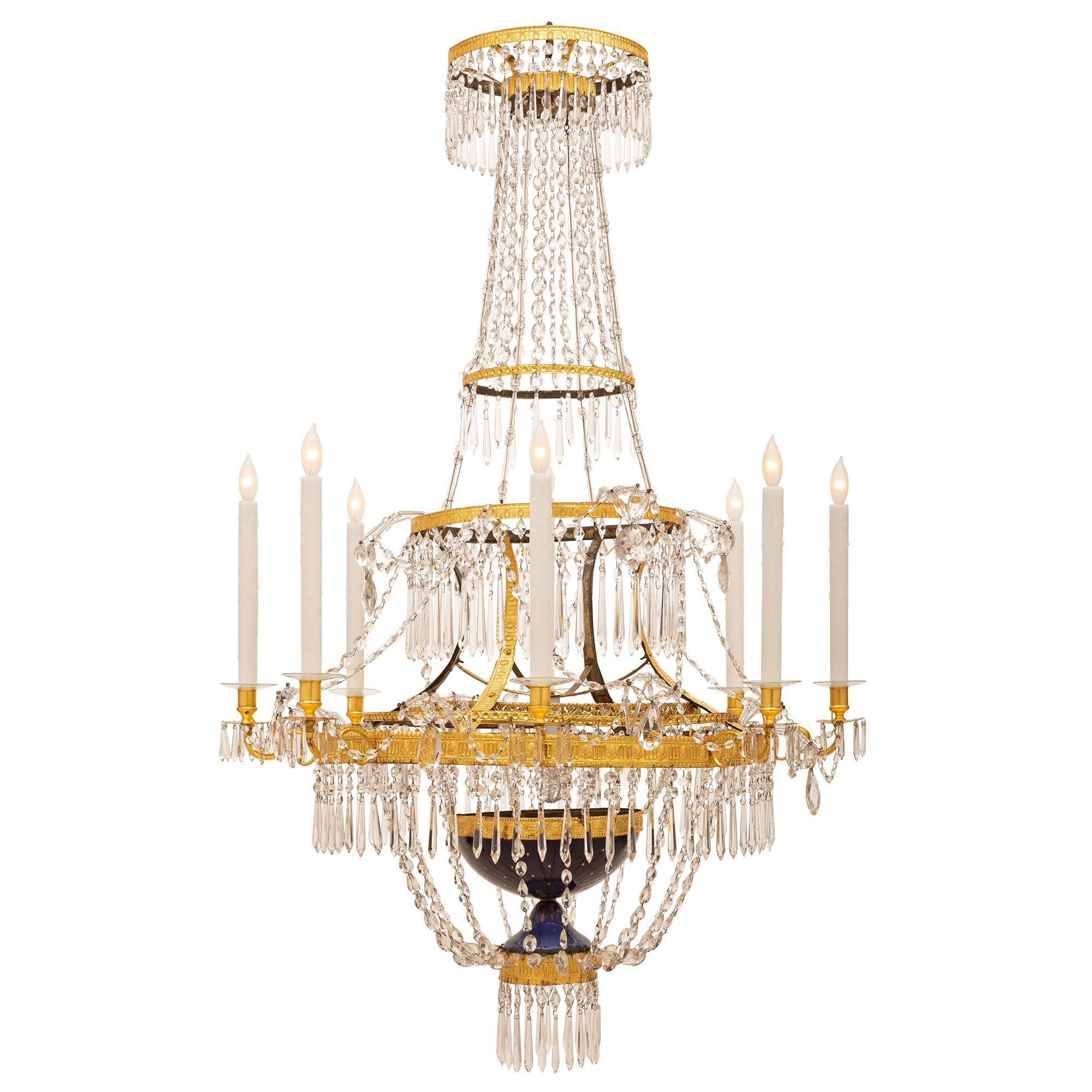 A spectacular and elegant Russian 19th century neo-classical st. crystal and gilt metal nine light chandelier. At the base above diamond pendants is an impressive blue glass urn shaped design element. The urn is decorated with gilt stars and foliate