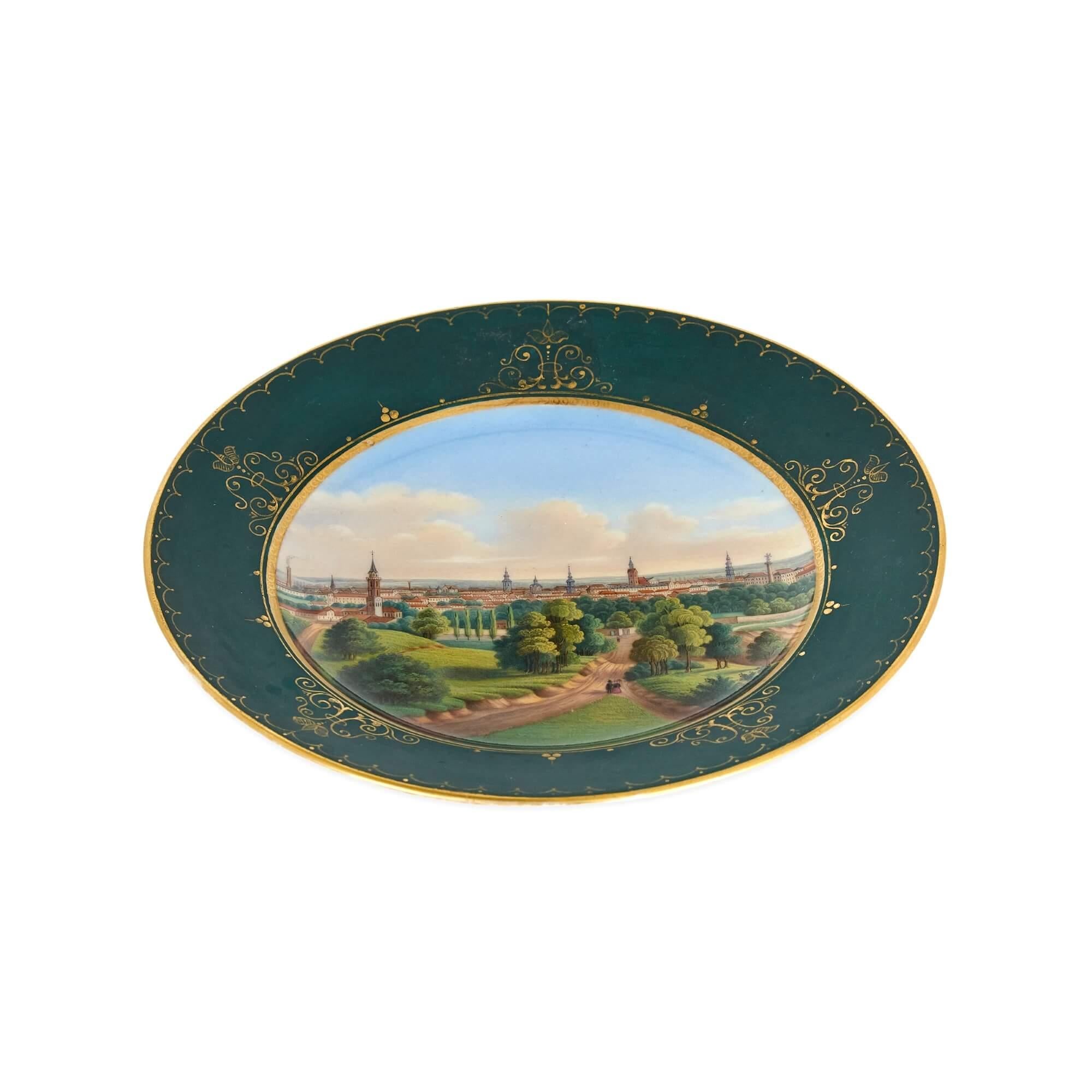 Russian 19th Century porcelain plate with painted landscape of Riga
Russian, c. 1820
Height 2.5cm, diameter 17cm

This antique Russian porcelain plate features a wide border in a green ground, decorated with arabesque details in gilt. To the centre,