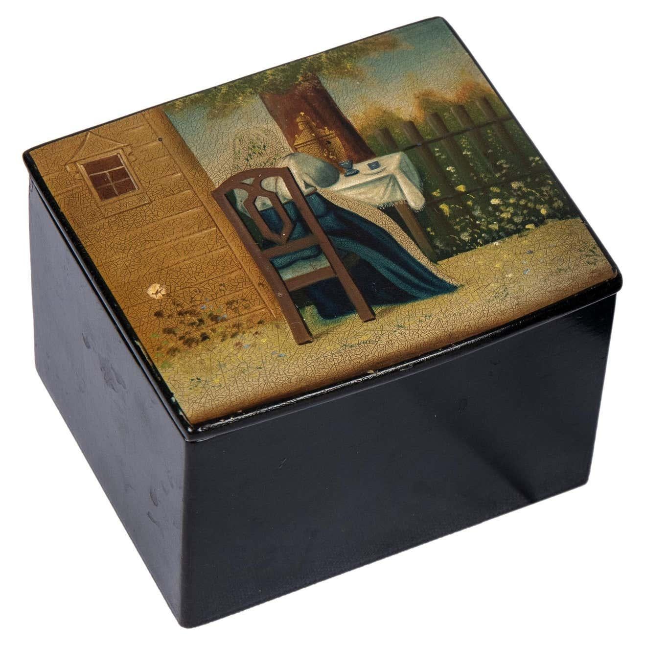 A delightful Russian tea caddy from the Romanov era, period of Tsar Alexander III, rectangular, the hinged cover painted with woman wearing a babushka seated outdoors next to a dacha, her back to the viewer enjoying tea from a samovar. The sides and