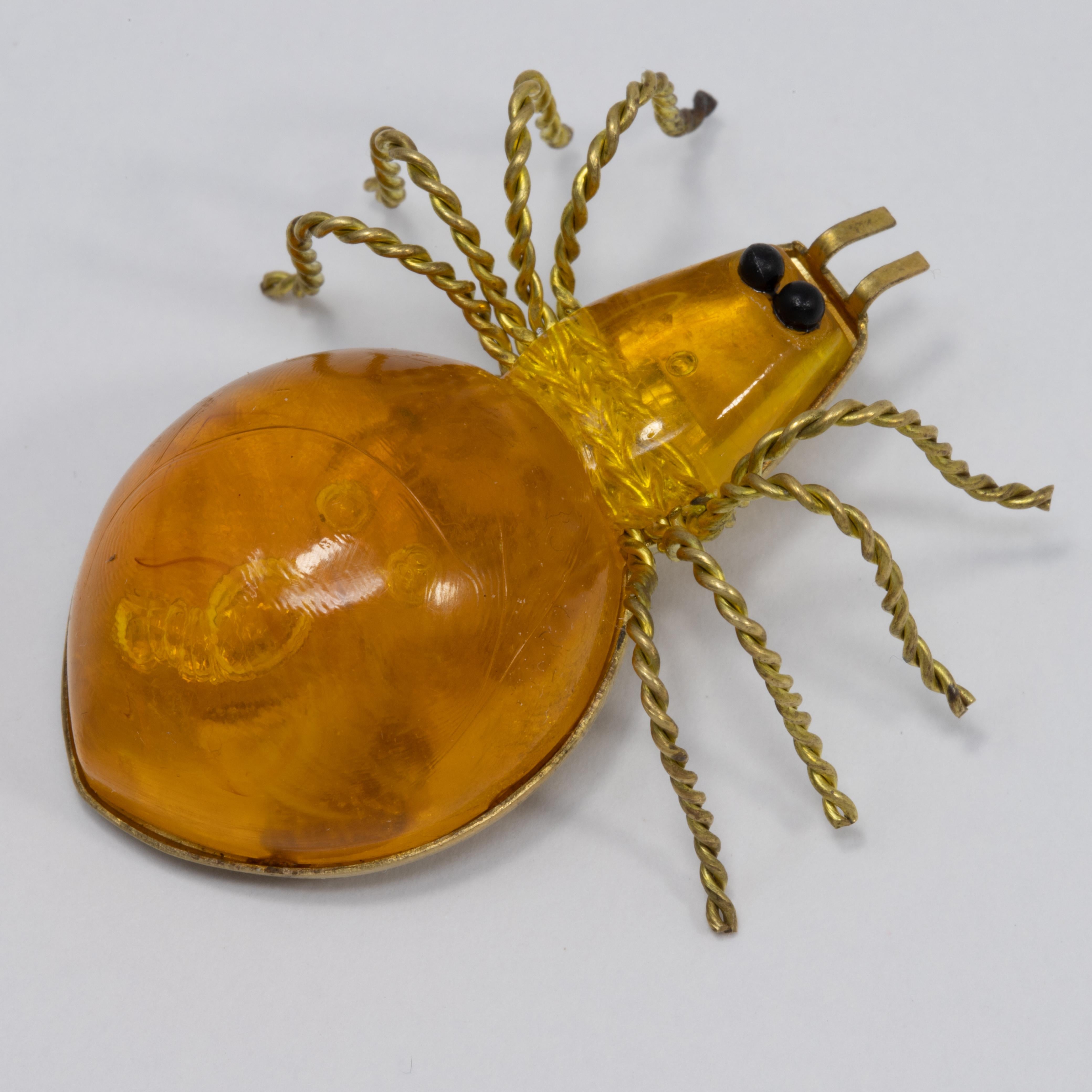 An exquisite spider brooch. This Russian pin is the perfect accessory, featuring an amber body set on a goldtone setting and accented with two round black eyes. The twisted wire legs add a quirky and artistic touch.

Hallmarks: 03P,