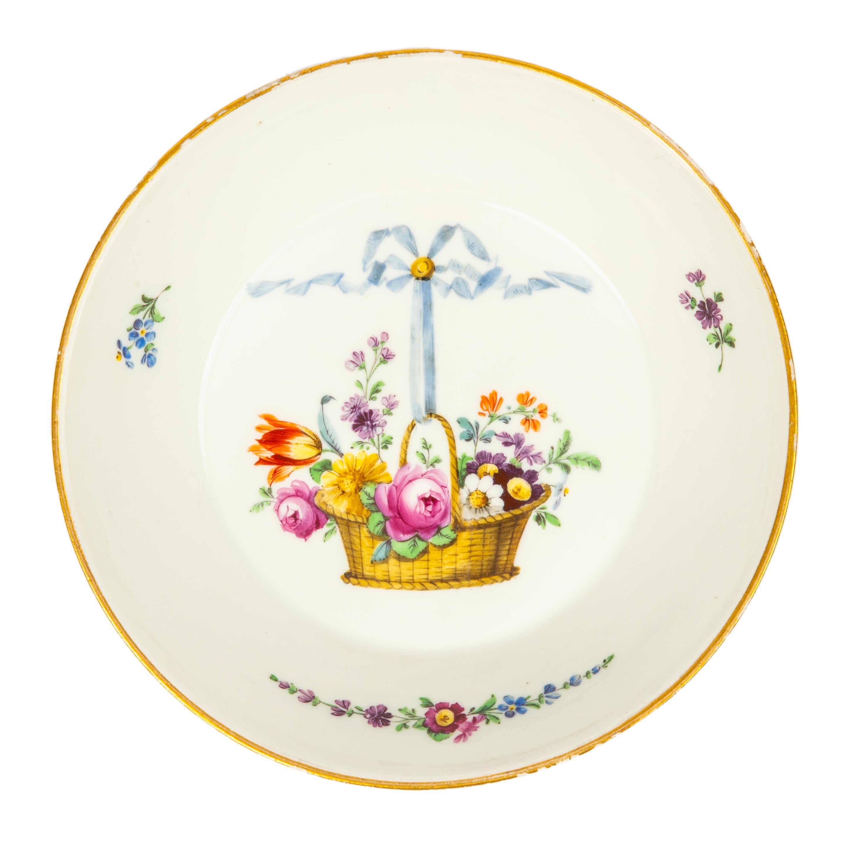 This rare 18th century Russian Porcelain covered cup and saucer is from the era of Catherine the Great (r. 1762-1796). Painted in the Marie Antoinette style with a flower basket held by a blue ribbon, with small floral clusters on white ground,