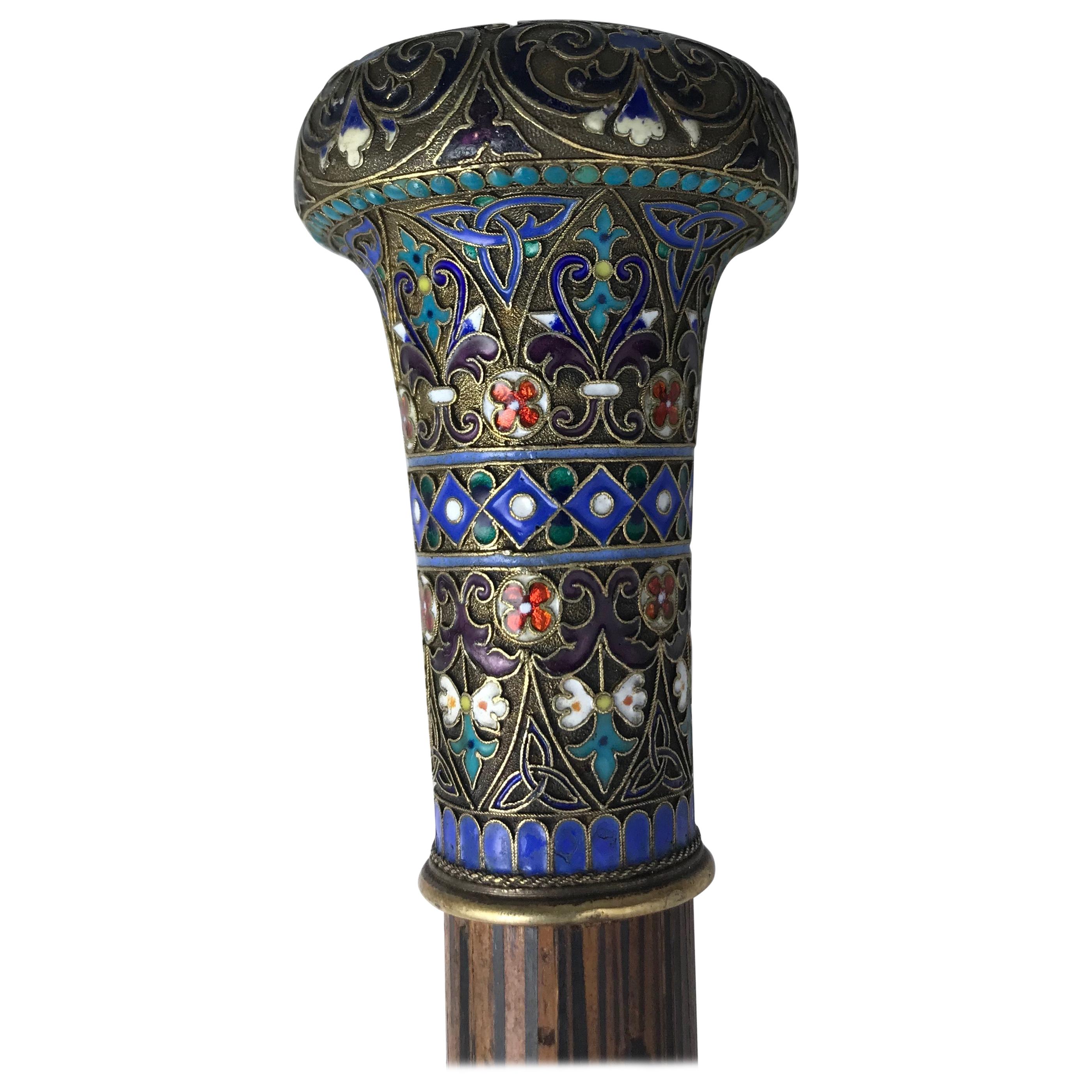 The capstan-shaped handle from the Romanov era, period of Tsar Nicholas II, decorated with vari-colored enamel scrolling foliage, florets, beaded and geometric motifs on silver, attached to a later tapered stick. 

Moscow, late 19th century,