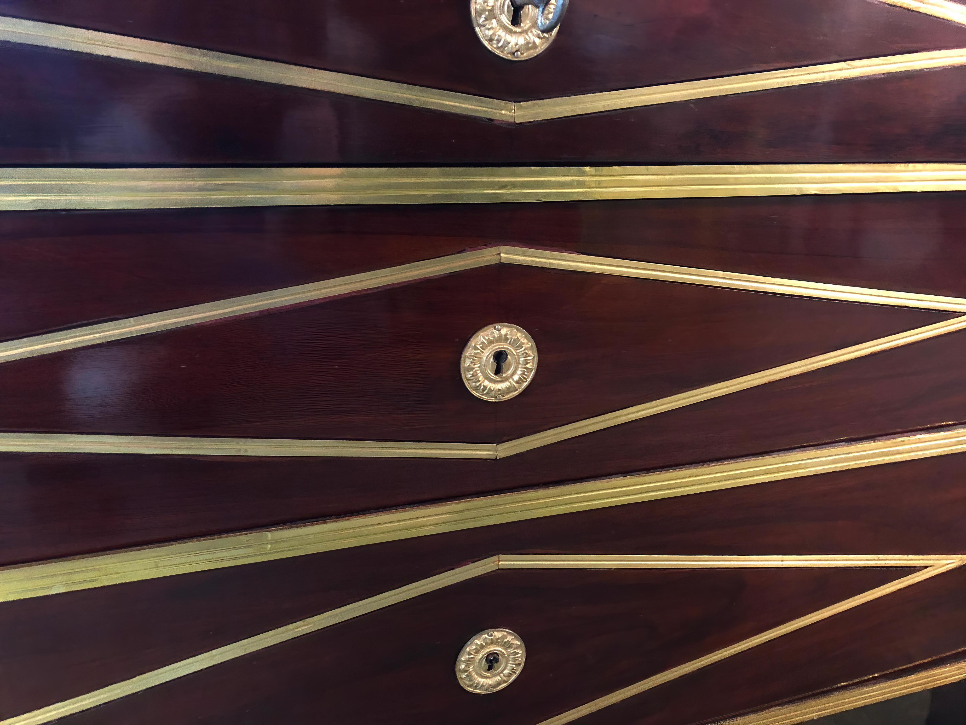 A fine Russian neoclassic mahogany three-drawer commode with brass trim and mounts, with diamond-shaped inlays and a stepped top, raised on canted square tapered legs.