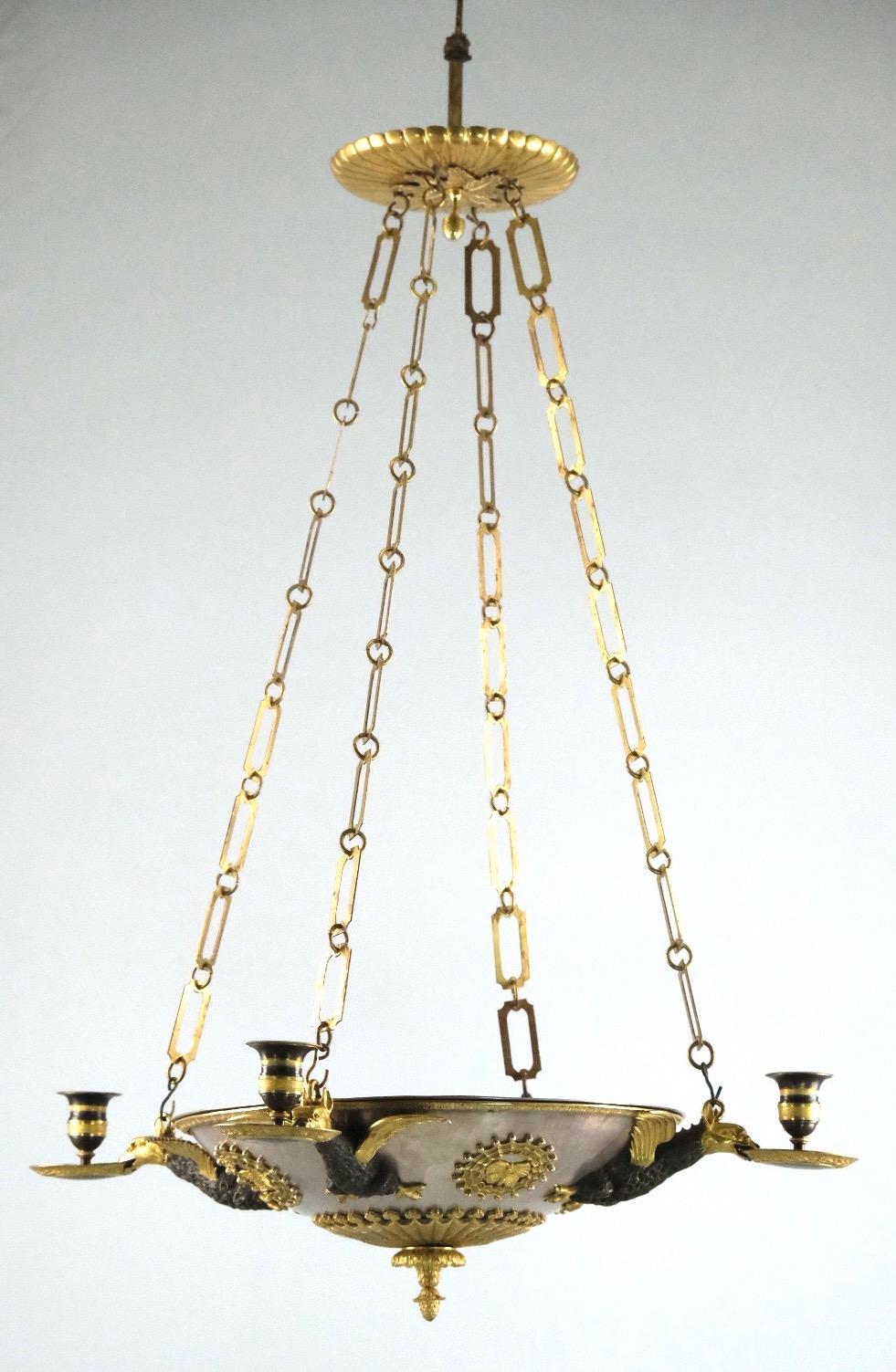 A unusual and high quality Russian chandelier made, ca 1810. The rounded bowl is made of thick copper that is silvered. The unshaped candleholders are held by flying dragons made of gilt and dark patinated bronze. All casting, enchasing and gilding