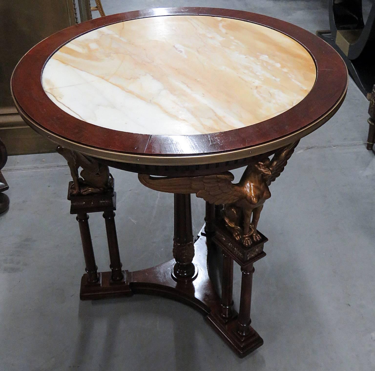 Russian Empire style centre table with a marble top on a carved wood base and brass trim.