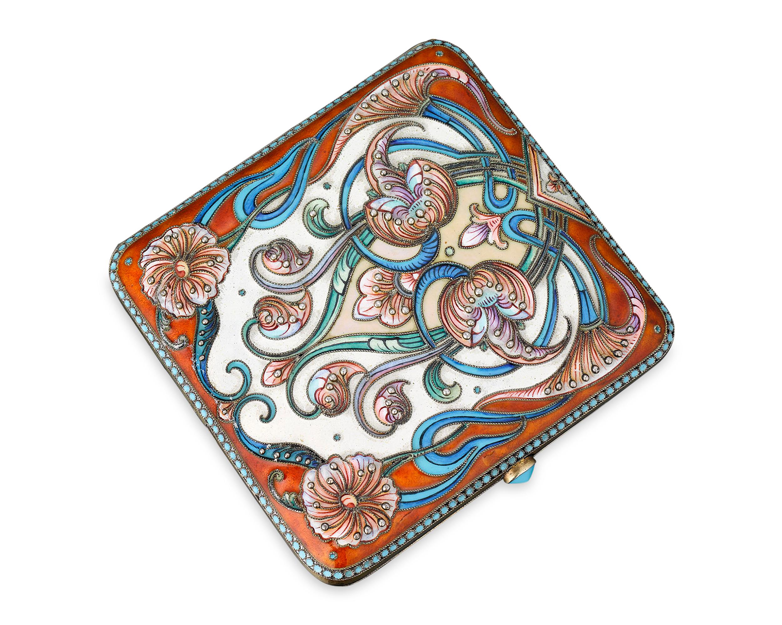 This elegant Russian enamel cigarette case is crafted of gilt silver and decorated with a bright floral design of cloisonné enamel. A turquoise-blue enamel thumb piece completes the sumptuous design. The case bears the 84 zolotniks mark of St.