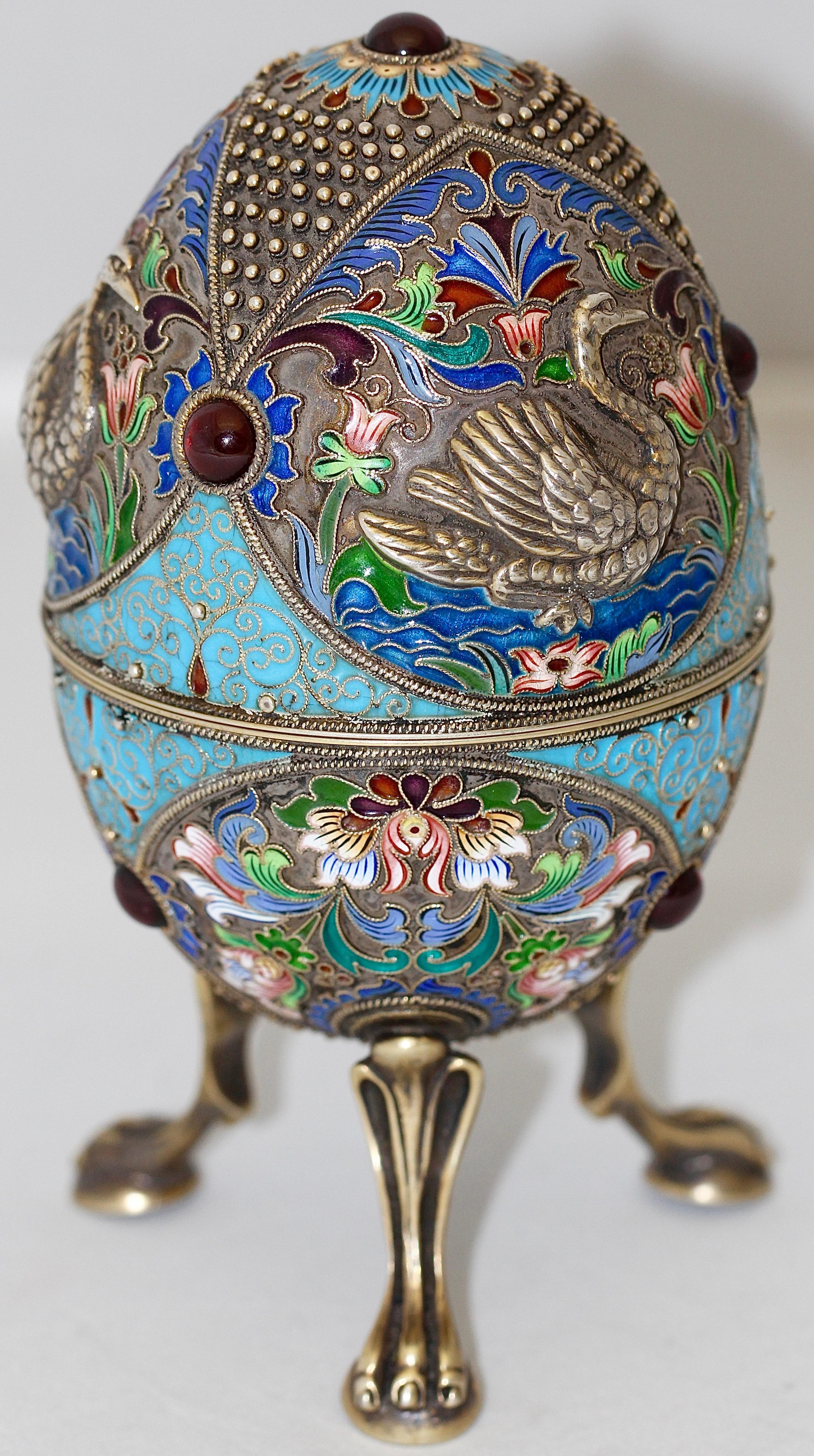 Russian Faberge Style Cloisonne Enamel Egg. 84 Silver H3 (NZ).

A beautifully shaped Russian silver-gilt and cloisonné enamel egg. Abundantly decorated with floral motives and swans. Set with red cabochon cut stones, probably garnets. On three lion