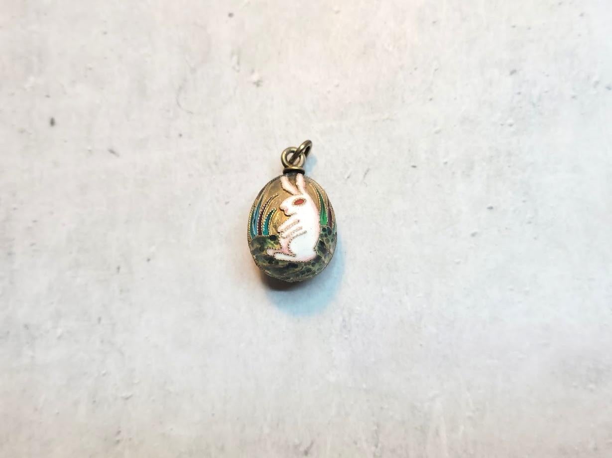 This stunning Russian Egg Charm Pendant showcases vibrant cloisonné enamel. It depicts funny rabbits surrounded by grass and leaves. The detailed design appears on both sides of the egg, making it a truly exquisite piece.

The following hallmarks