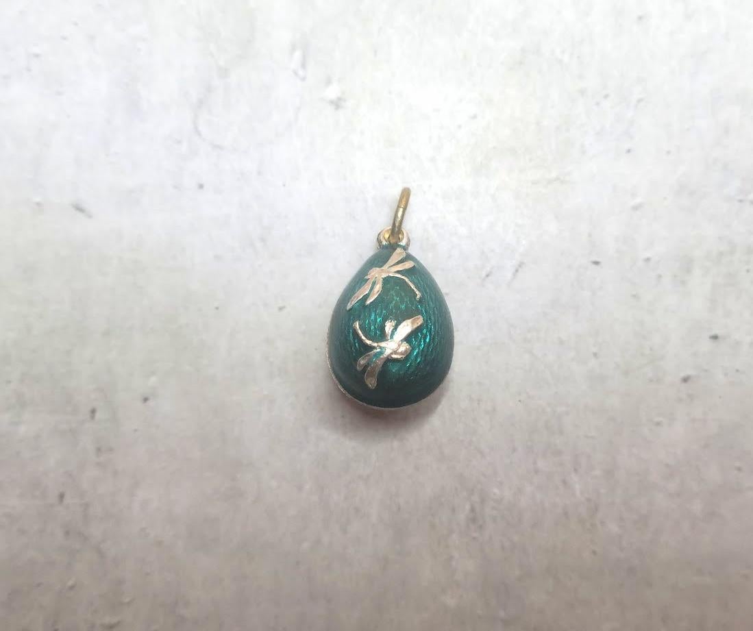 This Fabergé pendant, a rare and historically significant piece, was crafted by the renowned workmaster Phillip Theodore Ringe. This silver gilded egg is covered in stunning emerald guilloche enamel and adorned with two charming dragonflies. 
Its