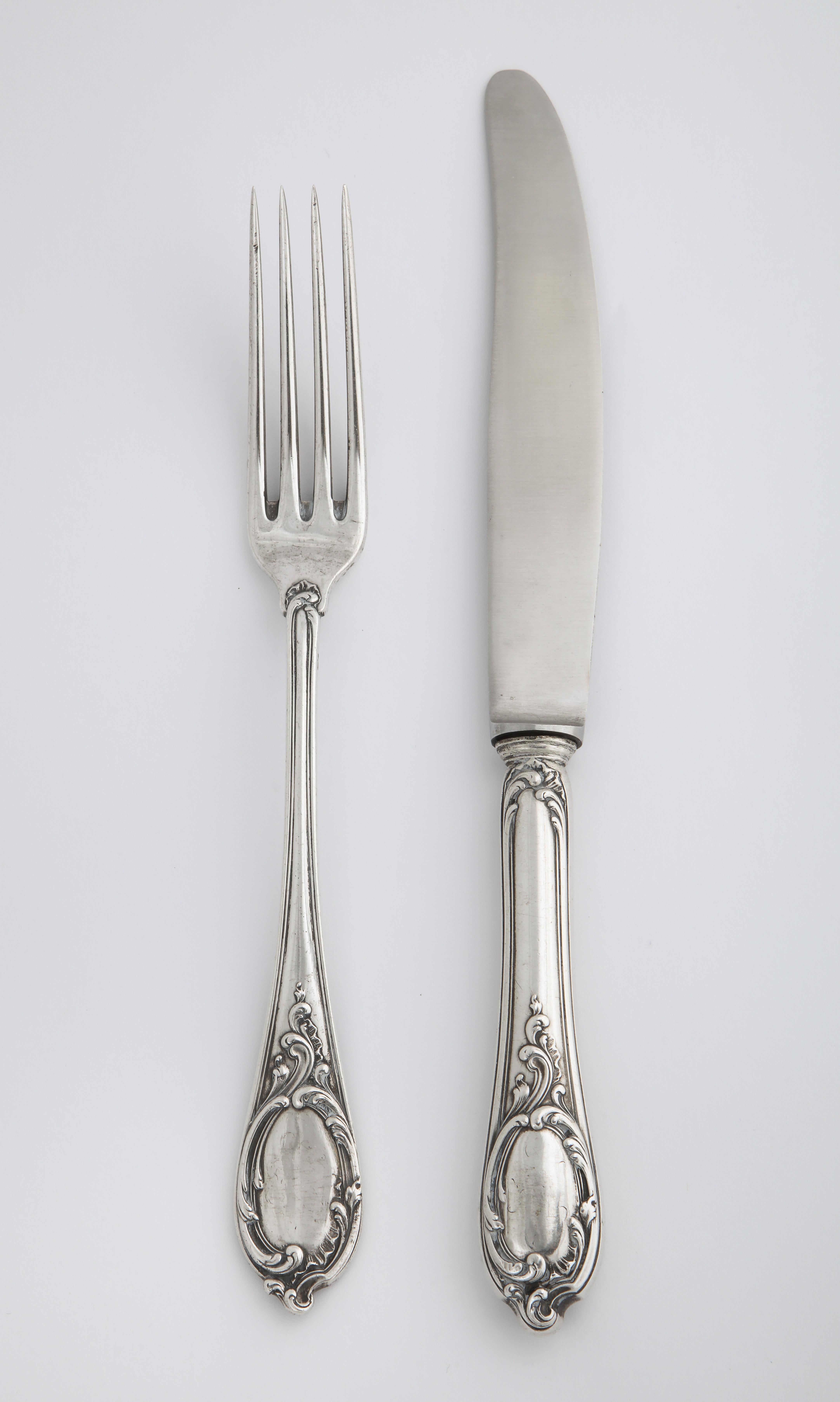 From the Romanov era, period of Czar Nicholas II, a silver knife and fork pair in the Rococo taste by Russia’s most famous silversmith, Carl Fabergé, each decorated with scrolls enclosing a vacant cartouche, the knife fitted with a later steel