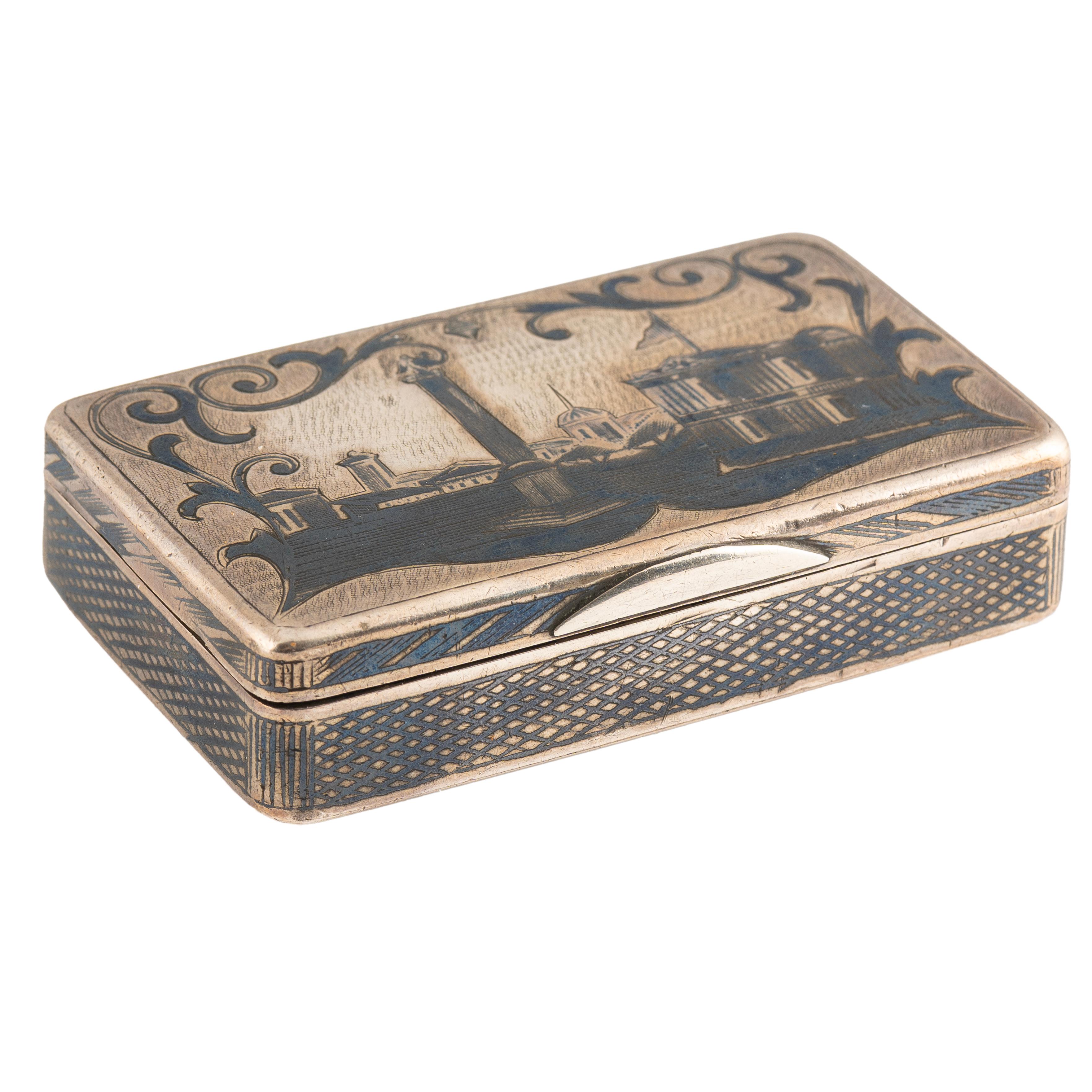 A Russian silver snuff box from the reign of Tsar Alexander III,  the hinged cover nielloed with a stylized scene of the Palace Square in St. Petersburg, surmounted by scrolls, the base with a small wooden ship moored before a walled fortress, with